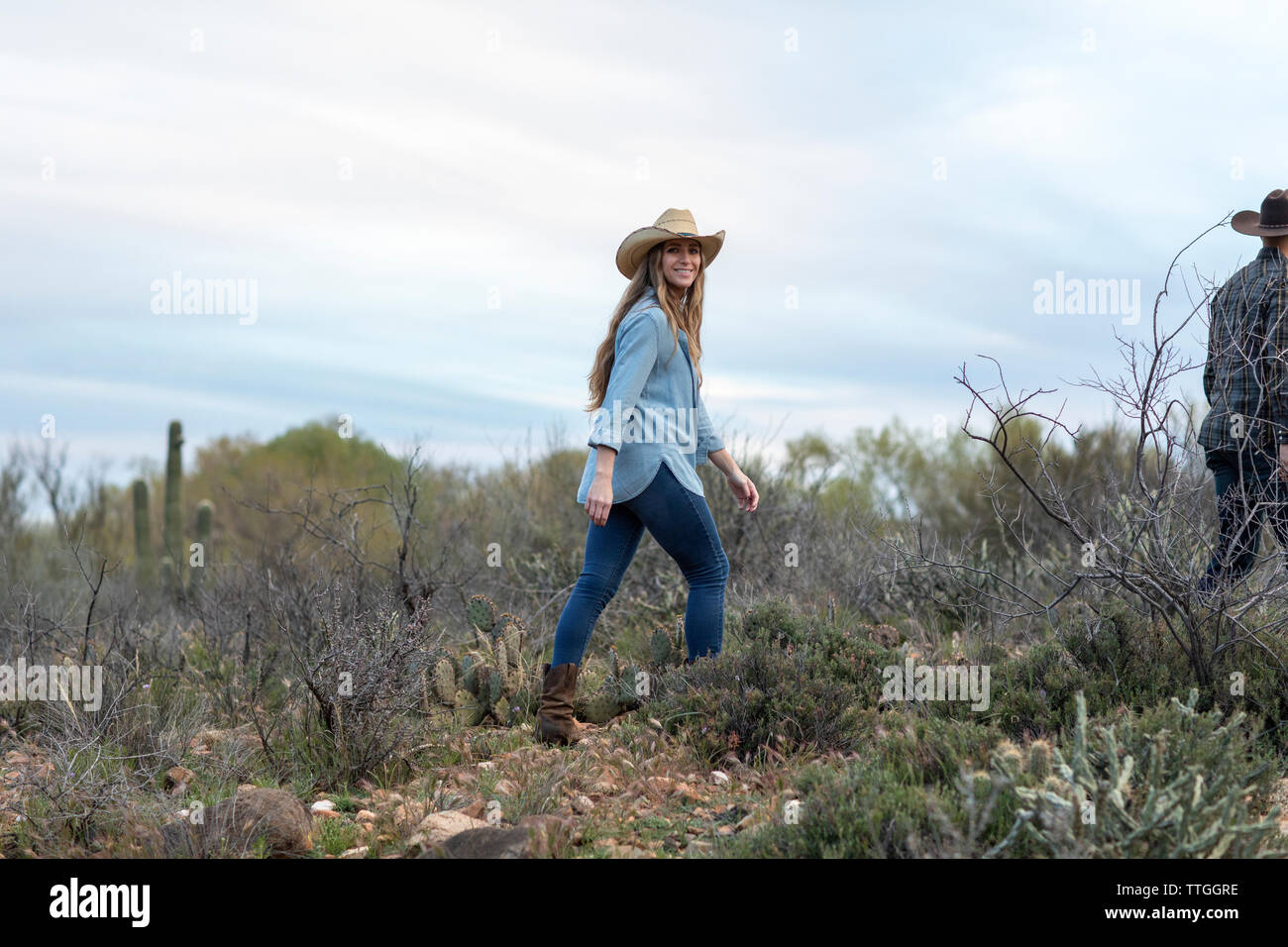 Western wear young woman walking in desert ranch Stock Photo