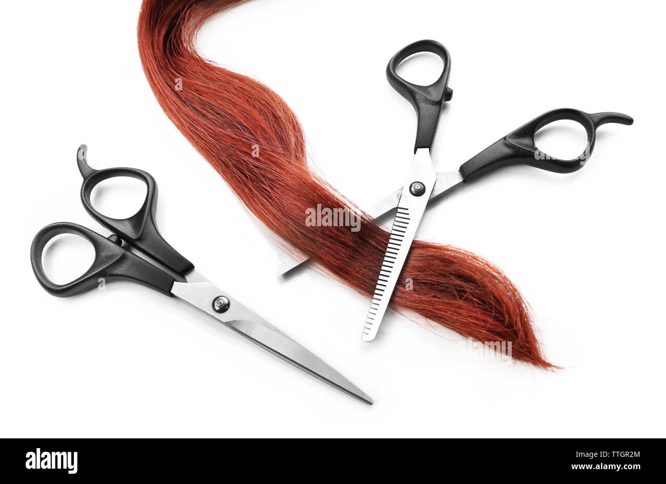Hairdresser's scissors with strand of red hair, isolated on white Stock Photo