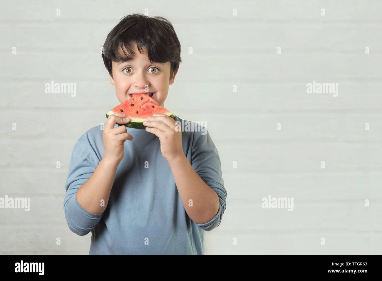 happy child eating watermelon on brick background Stock Photo