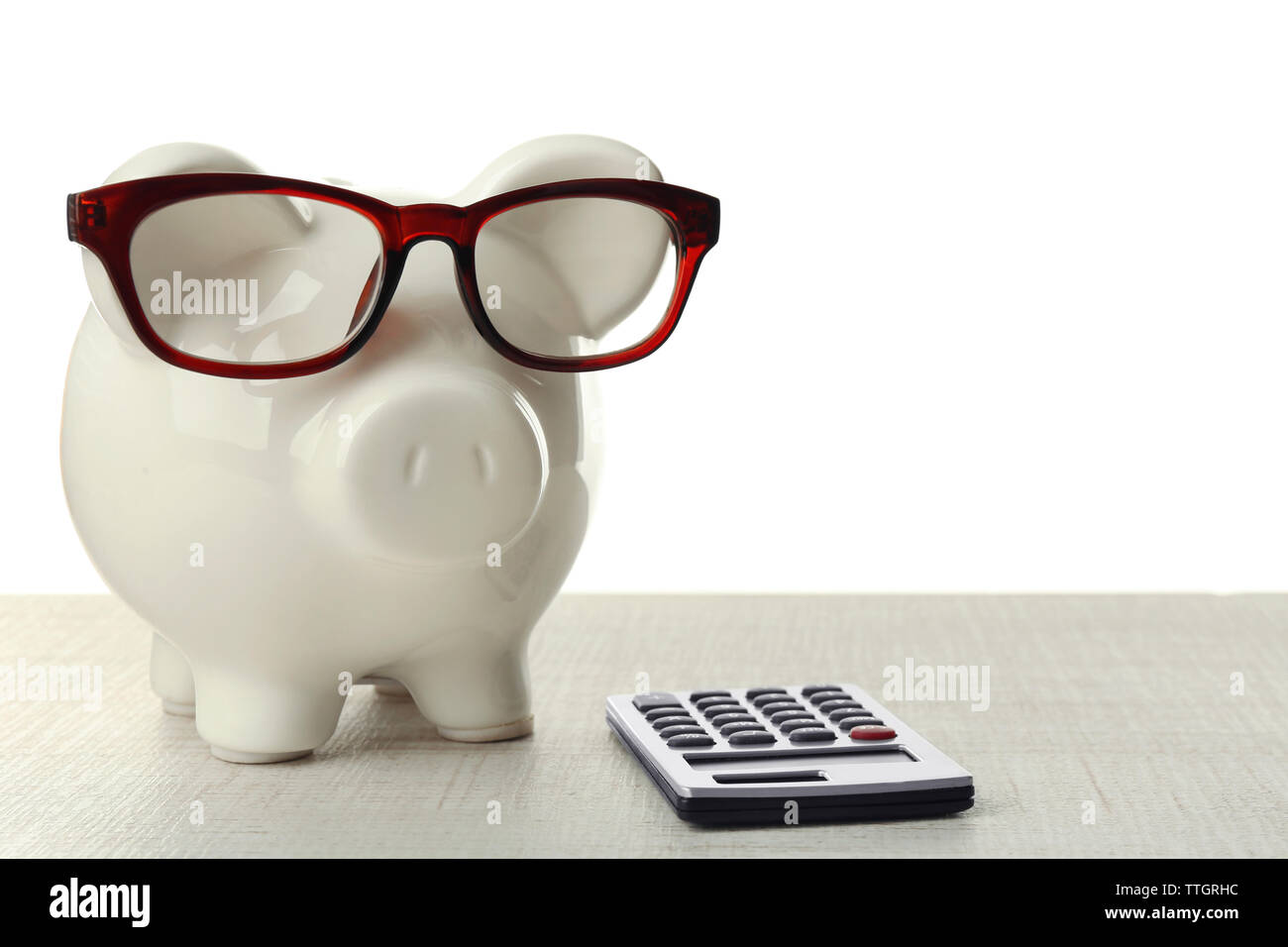 Piggy bank with glasses and calculator on white background Stock Photo ...