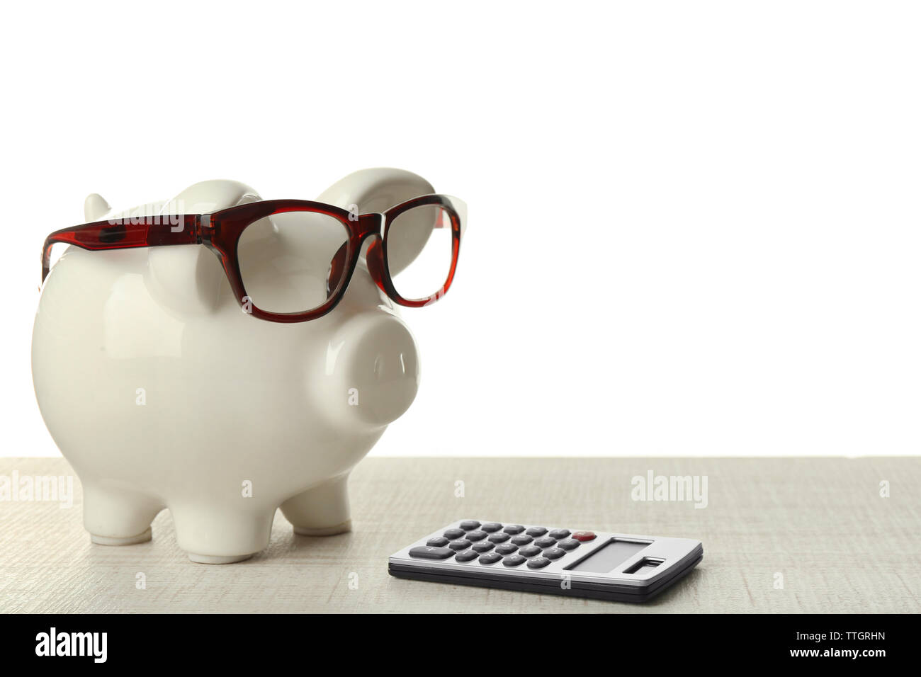 Piggy bank with glasses and calculator on white background Stock Photo ...