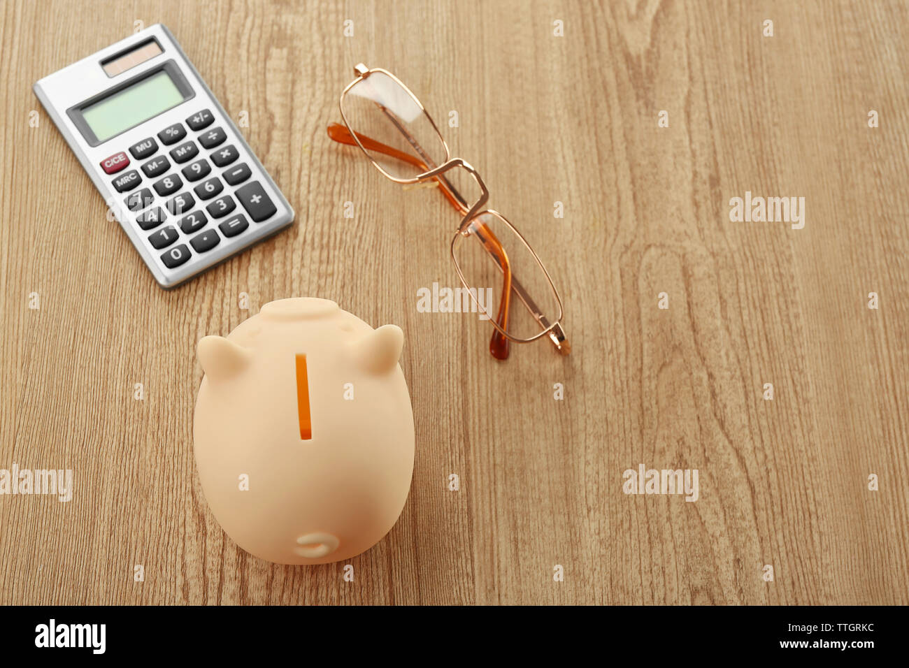 Beige piggy bank with glasses and calculator on wooden background Stock ...