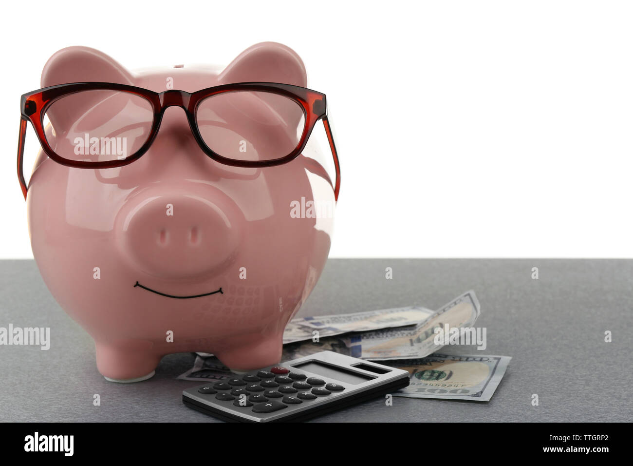 Pink piggy bank with dollar banknotes, glasses and calculator on white ...