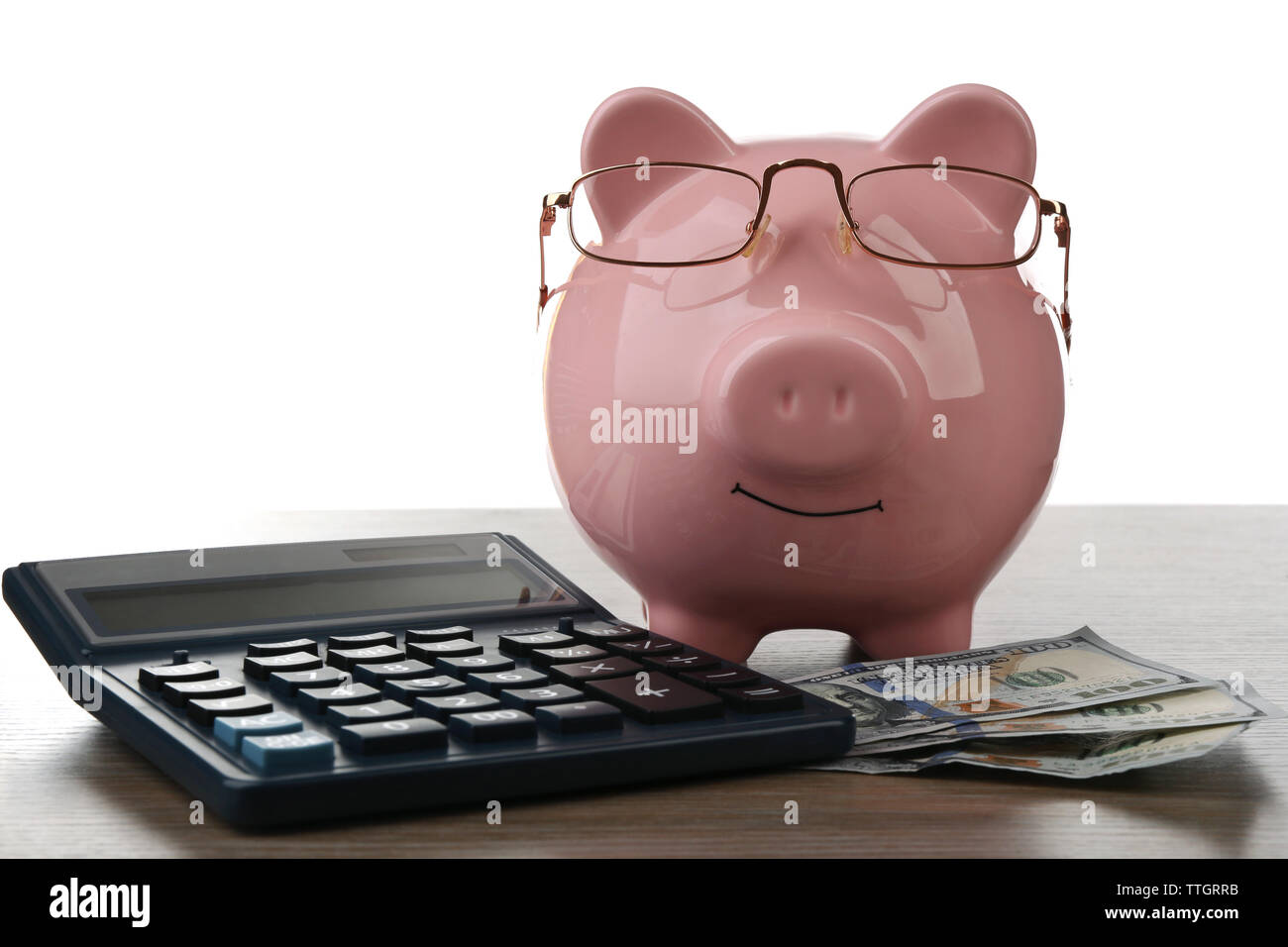 Pink piggy bank with dollar banknotes, glasses and calculator on white ...