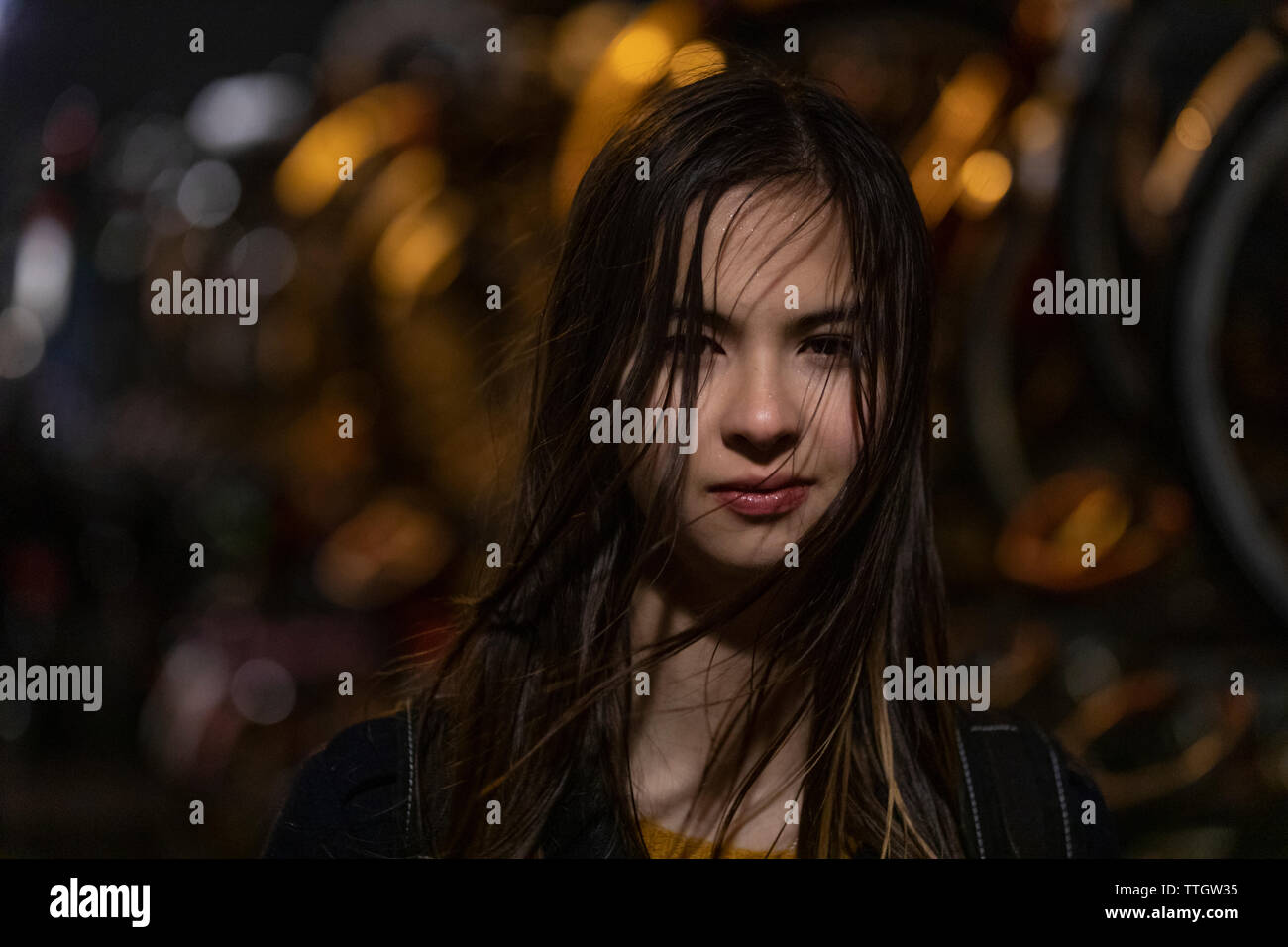 Beautiful woman with wet hair standing in rain on the street at night. Stock Photo
