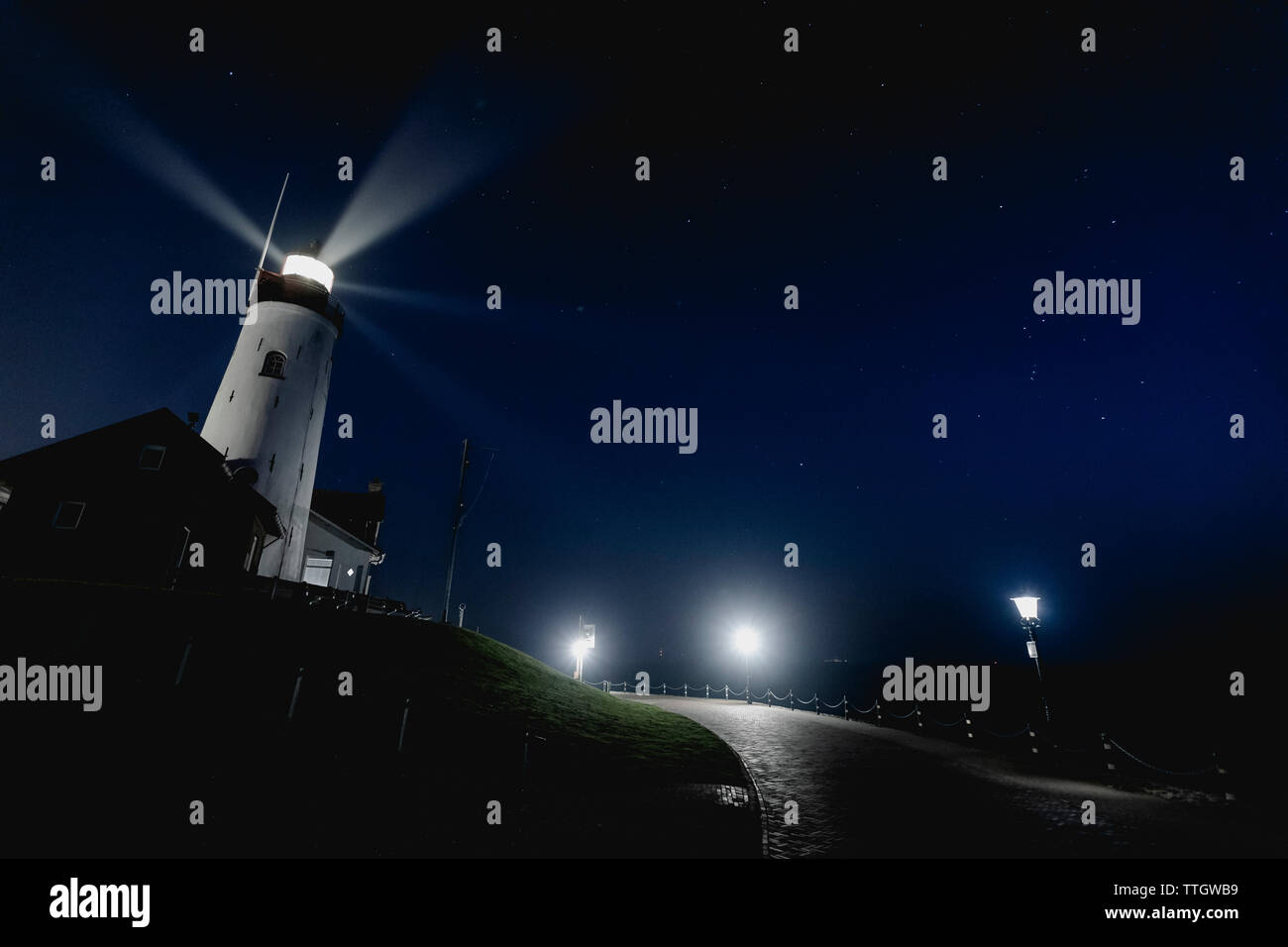 The lighthouse with with light stream on night sky with seeing stars. Stock Photo