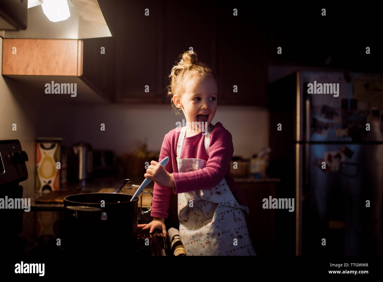 Happy girl looking away while preparing food in kitchen at home Stock Photo