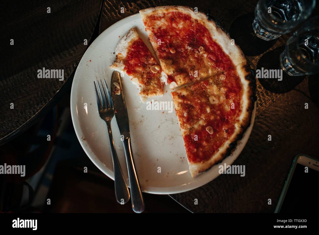 gluten free & vegan Pizza on a plate with knife & fork in restaurant Stock Photo