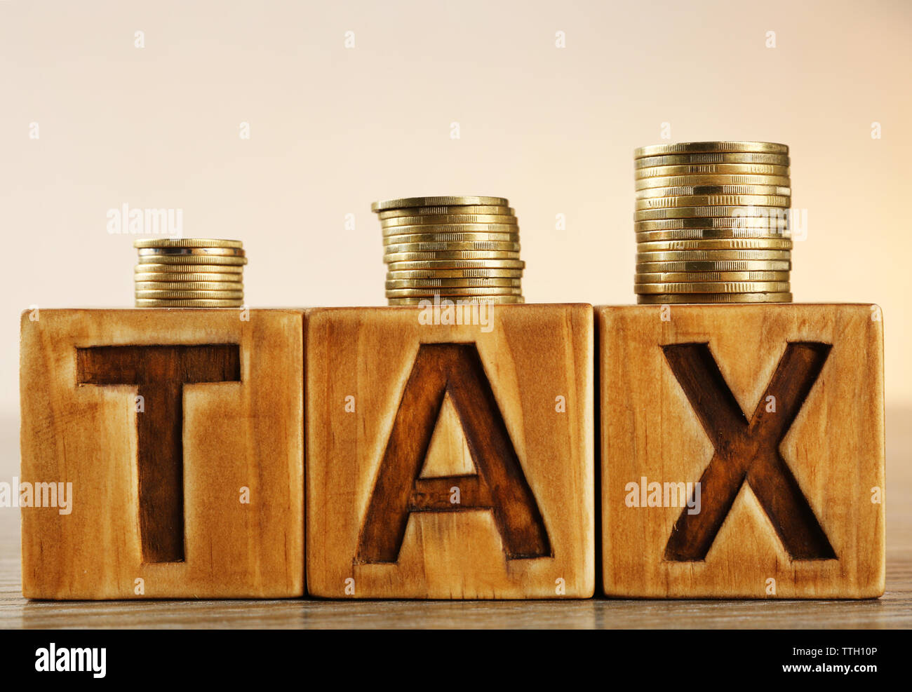 Tax concept with wooden blocks and coins on table Stock Photo - Alamy