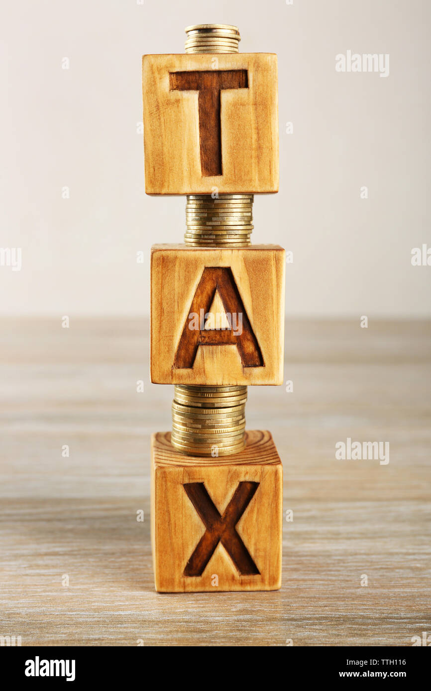 Tax concept with wooden blocks and coins on table Stock Photo - Alamy