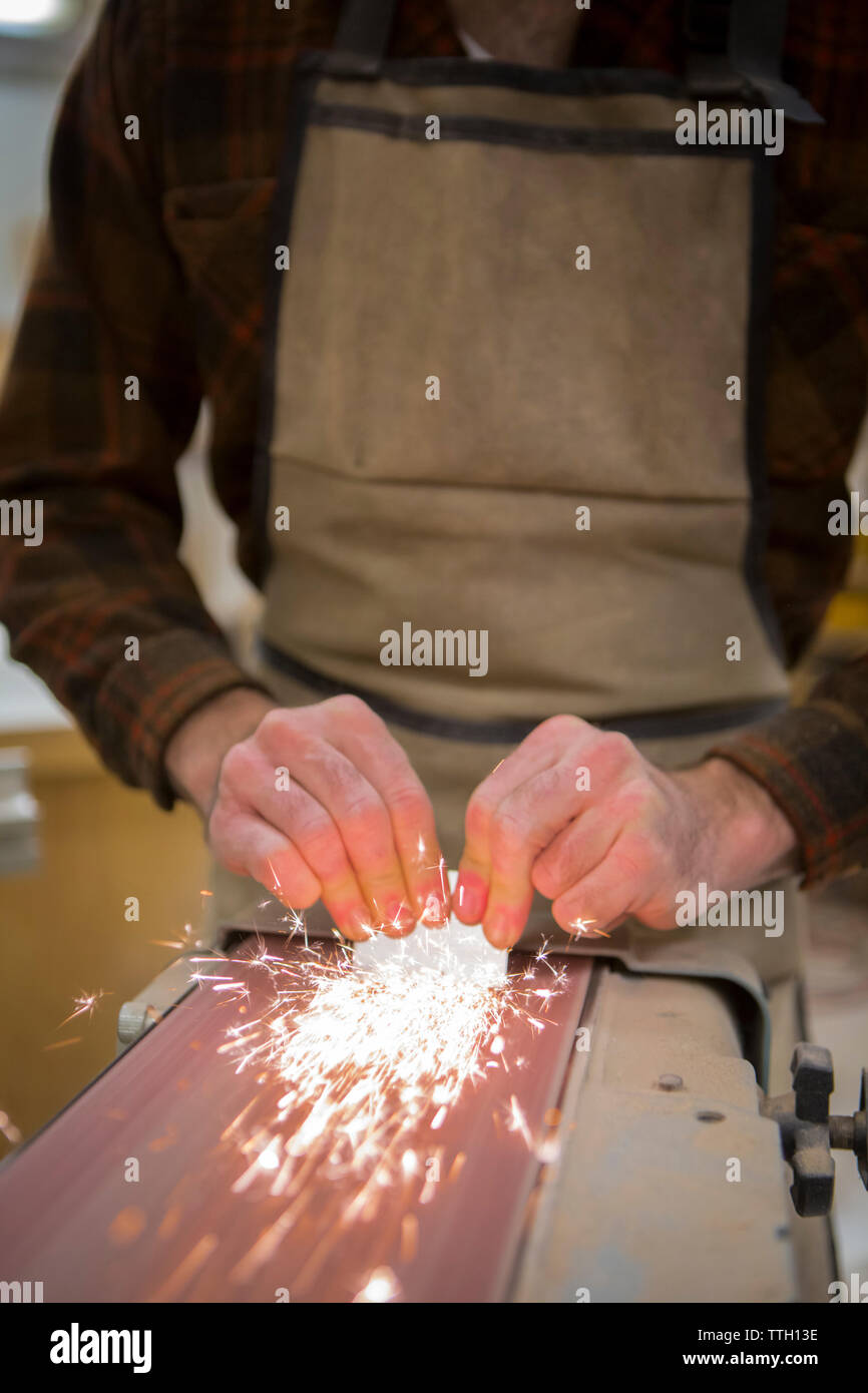 Midsection of carpenter working with electrical sanding machine at workshop Stock Photo