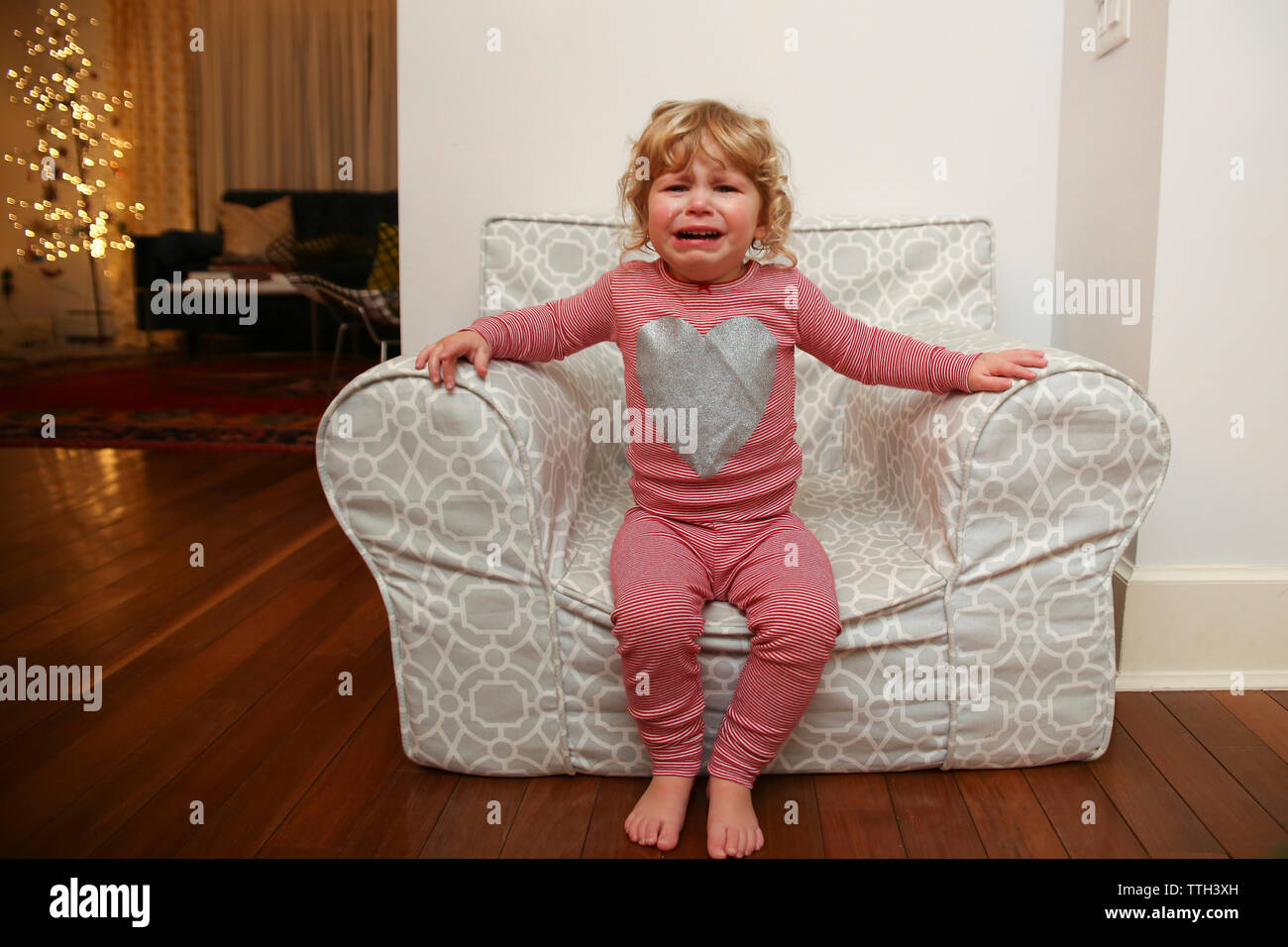 Portrait of girl crying while sitting on armchair at home Stock Photo