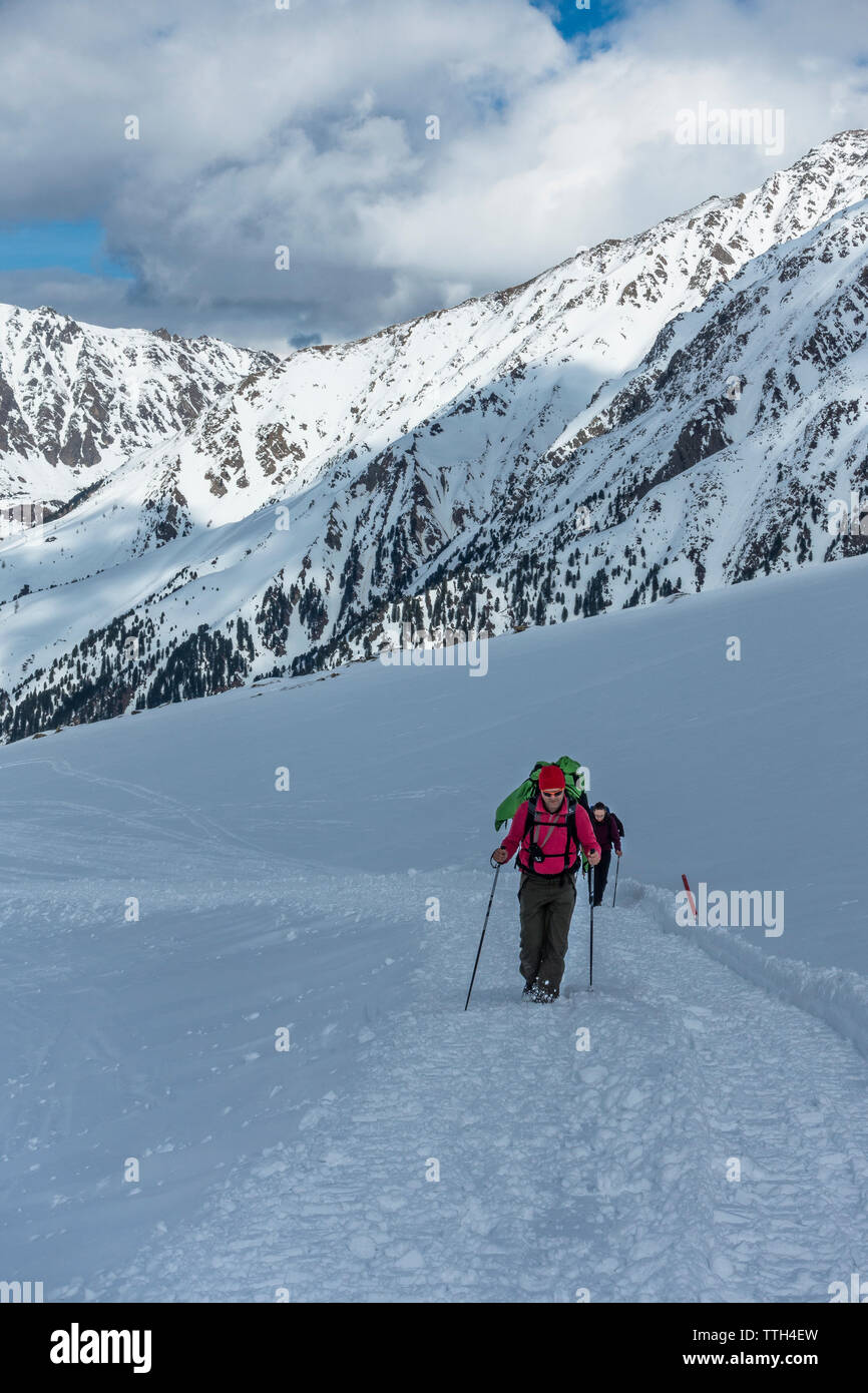 Active couple ascending a trail in the snowy Austrian alps Stock Photo