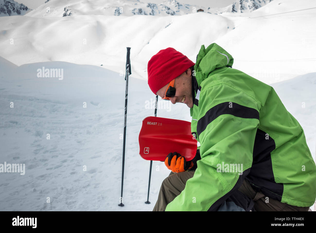 Portrait of a smiling man storing away an avalanche shovel Stock Photo