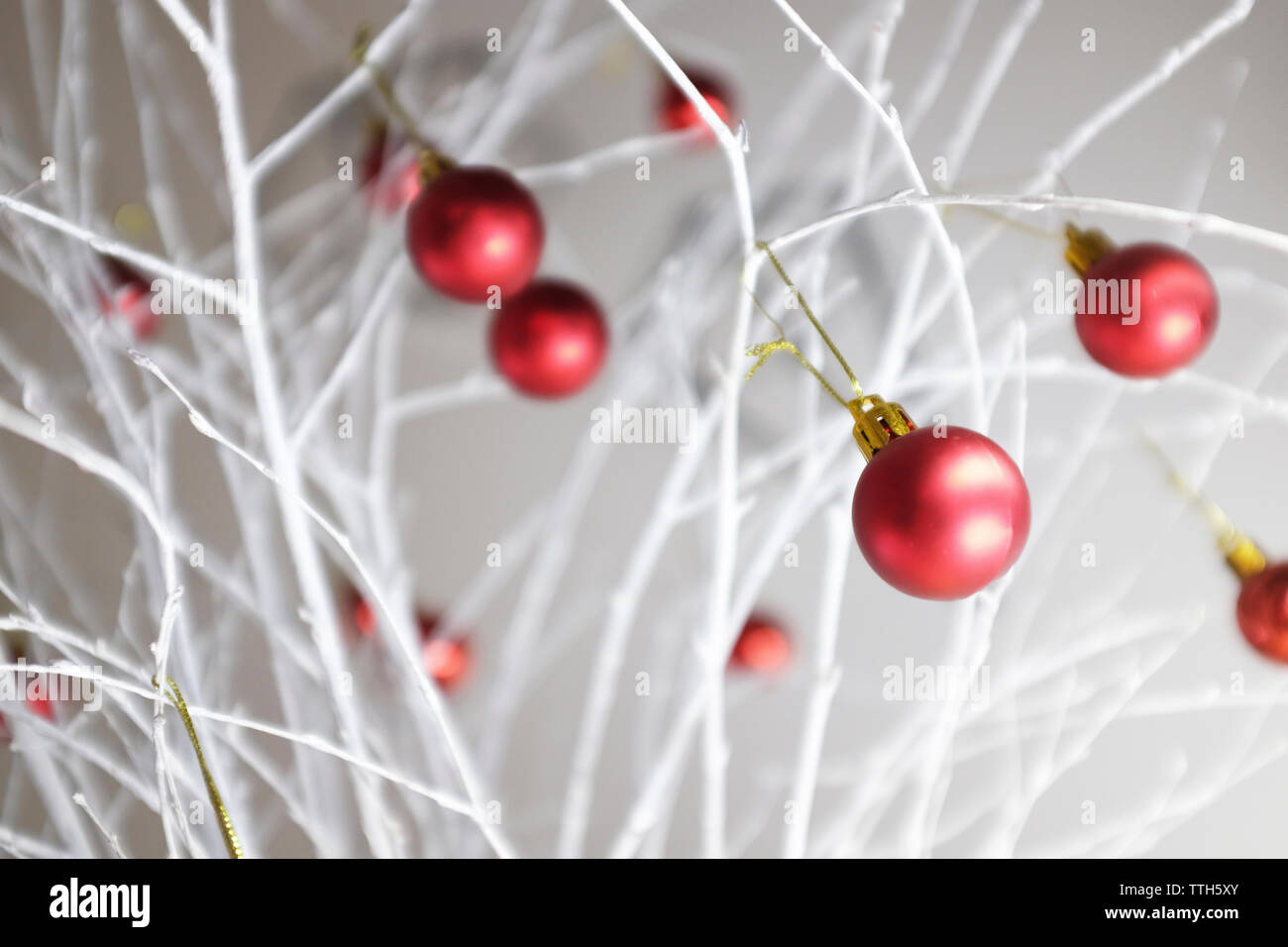 Close-up of red christmas baubles decorated on white branches at home Stock Photo