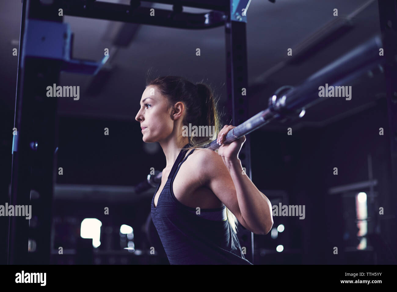 Portrait of young woman training at fitness centre with barbell. Stock Photo