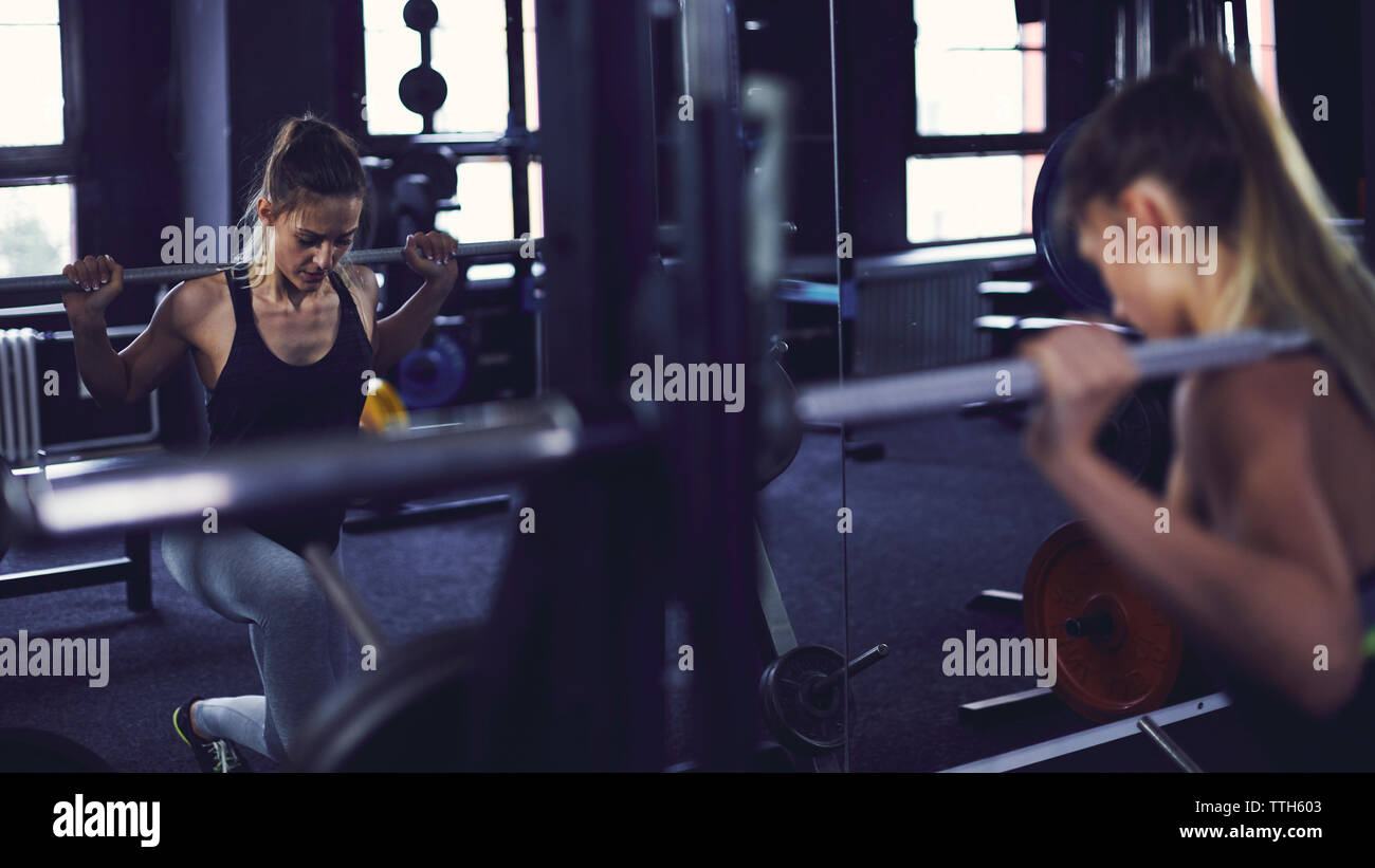 Reflection of young woman doing legs work out at fitness centre Stock Photo