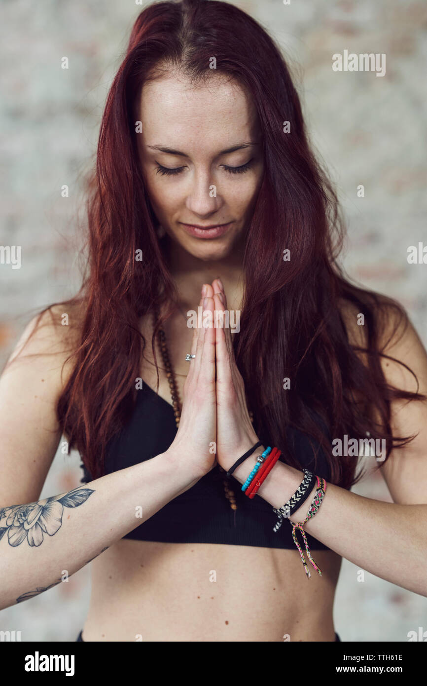 Young female in yoga pose with eyes closed by the brick wall Stock Photo