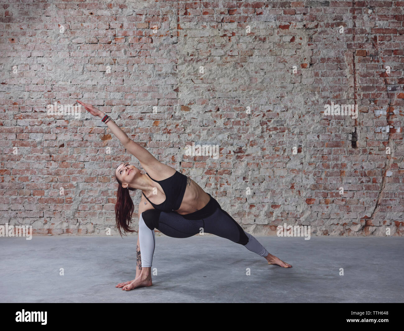 Young female in yoga pose by the brick wall Stock Photo