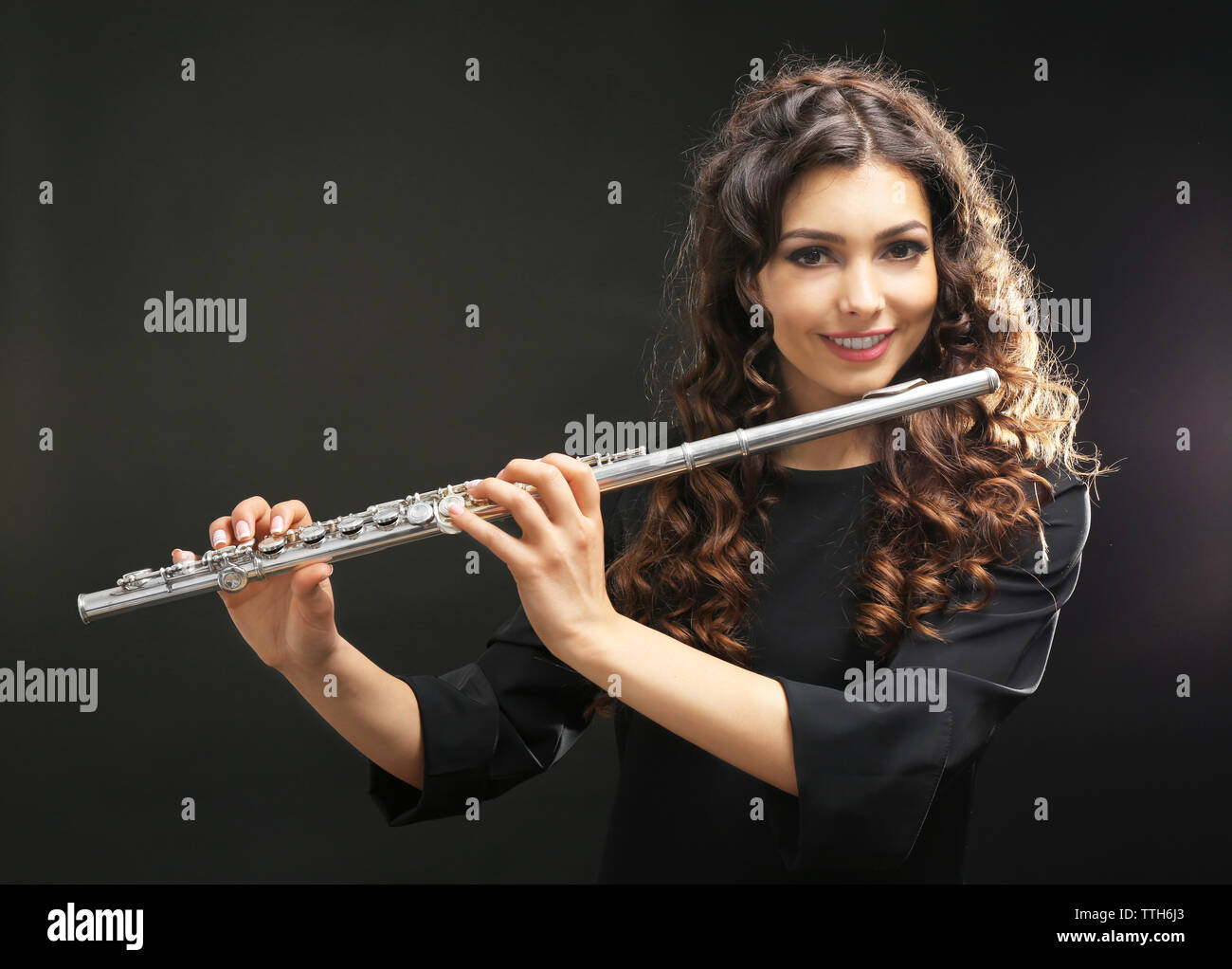 Beautiful young woman with flute on black background Stock Photo - Alamy