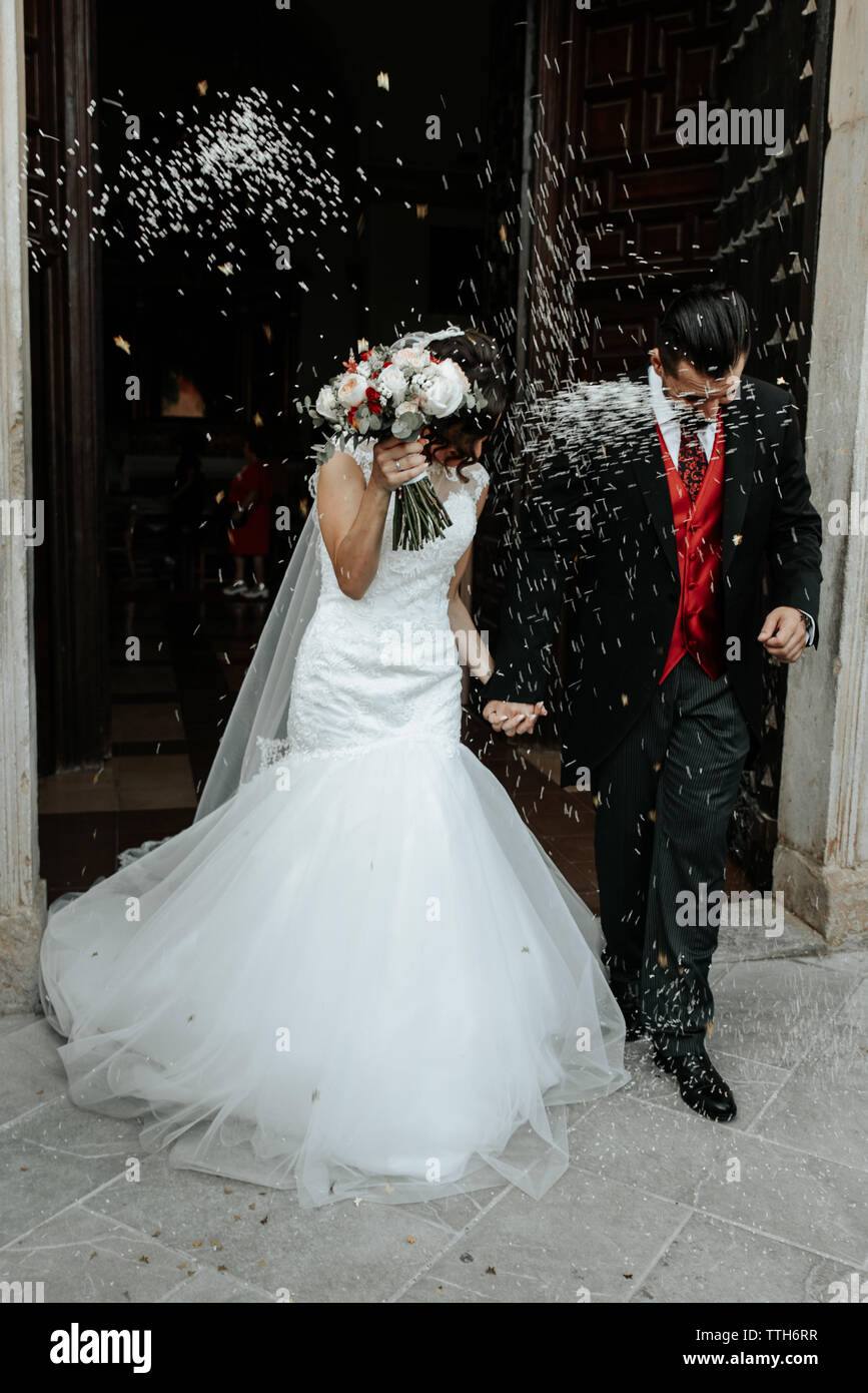 People throw rice on newlyweds walking out of the church Stock Photo