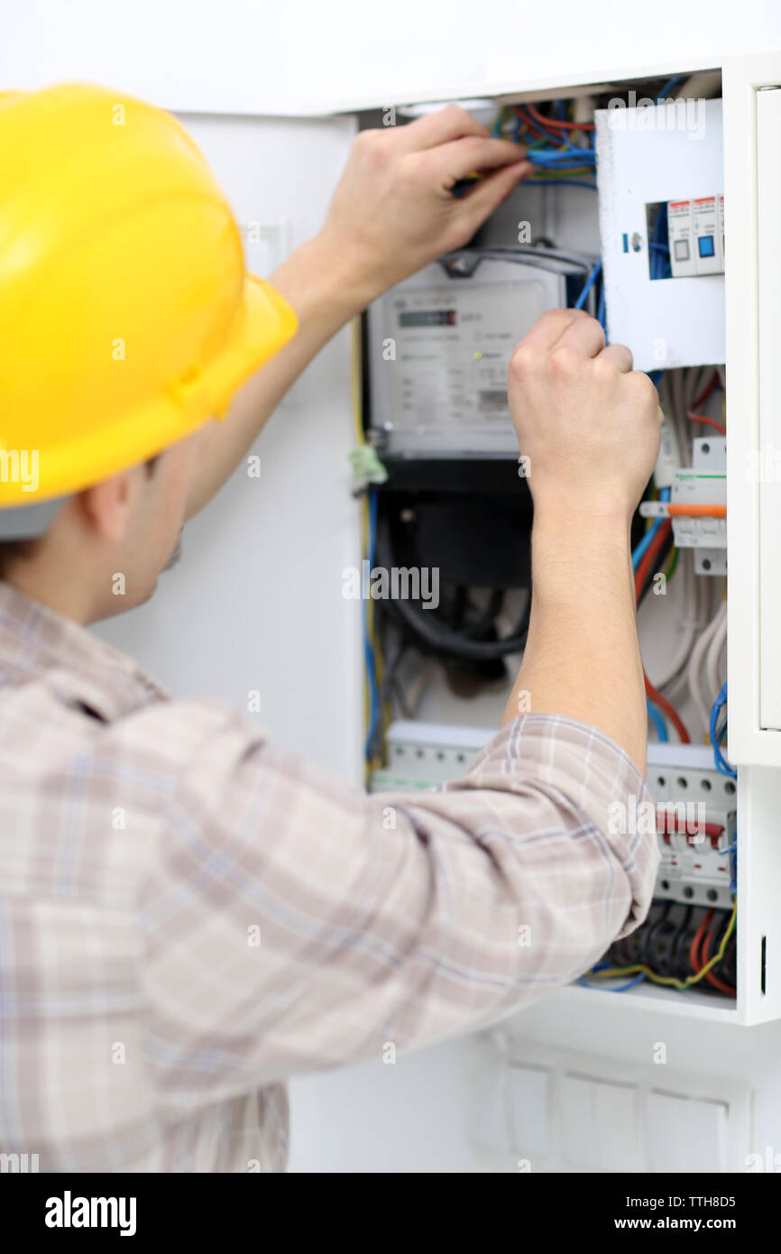 Young electrician checking voltage in fuse board Stock Photo