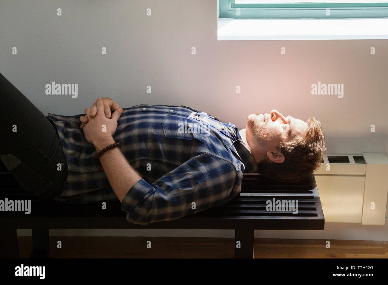 Side view of businessman sleeping on bench in creative office Stock Photo