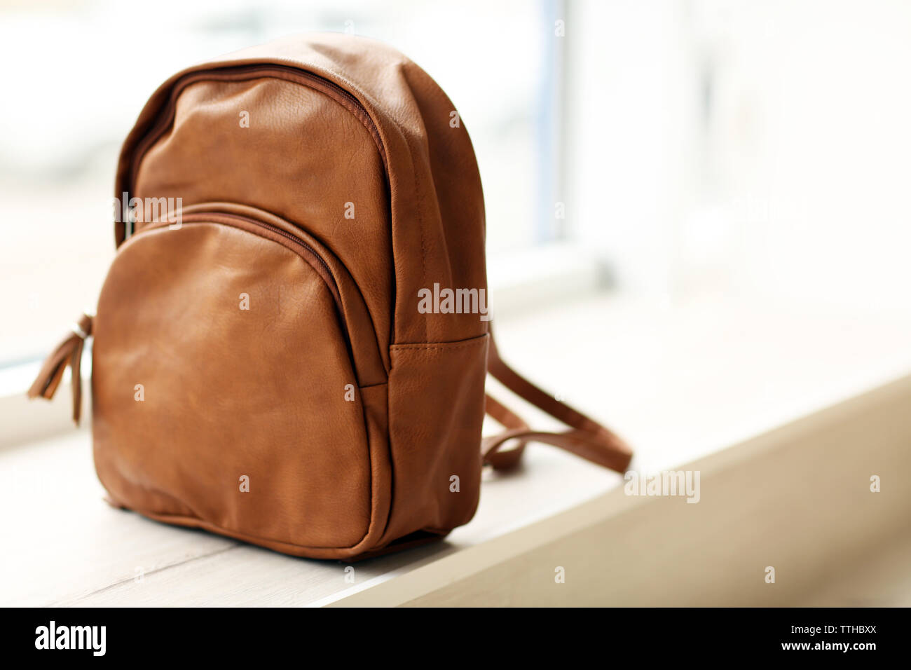 Brown leather backpack on the windowsill. Stock Photo