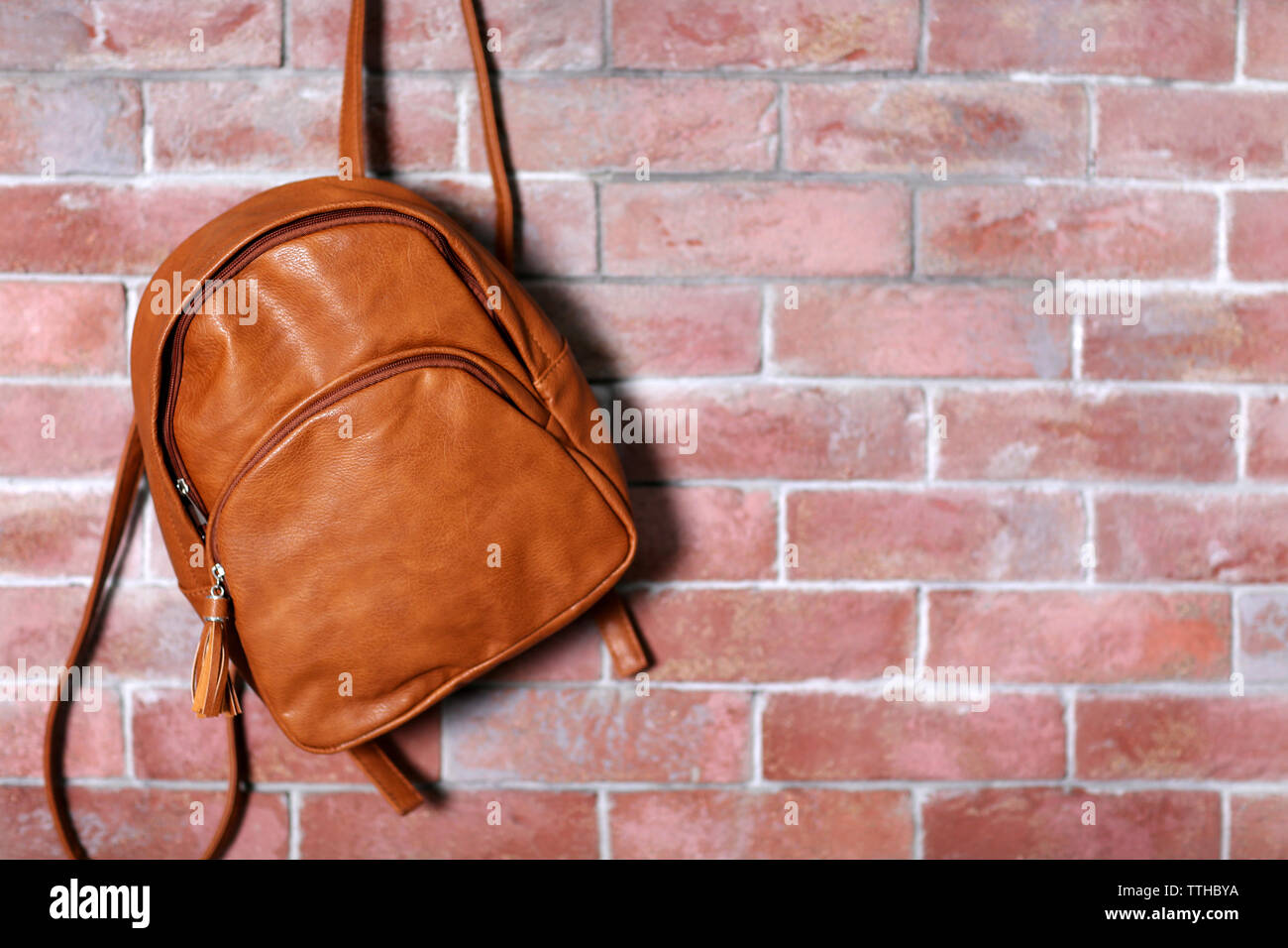 Brown leather backpack hanging on the brick wall Stock Photo Alamy