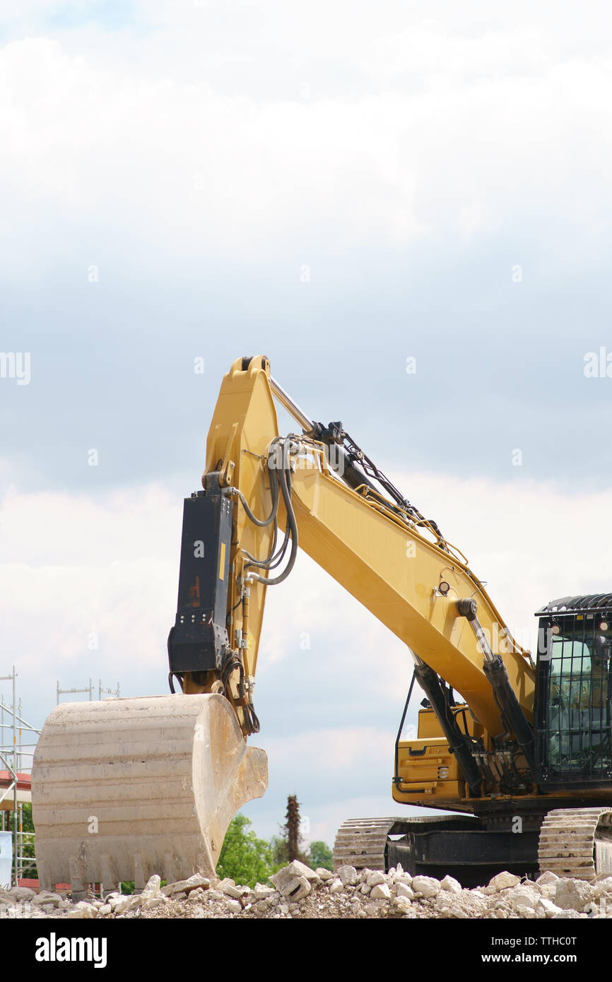 A non-working excavator stands on the rubble heap of a construction site. Stock Photo