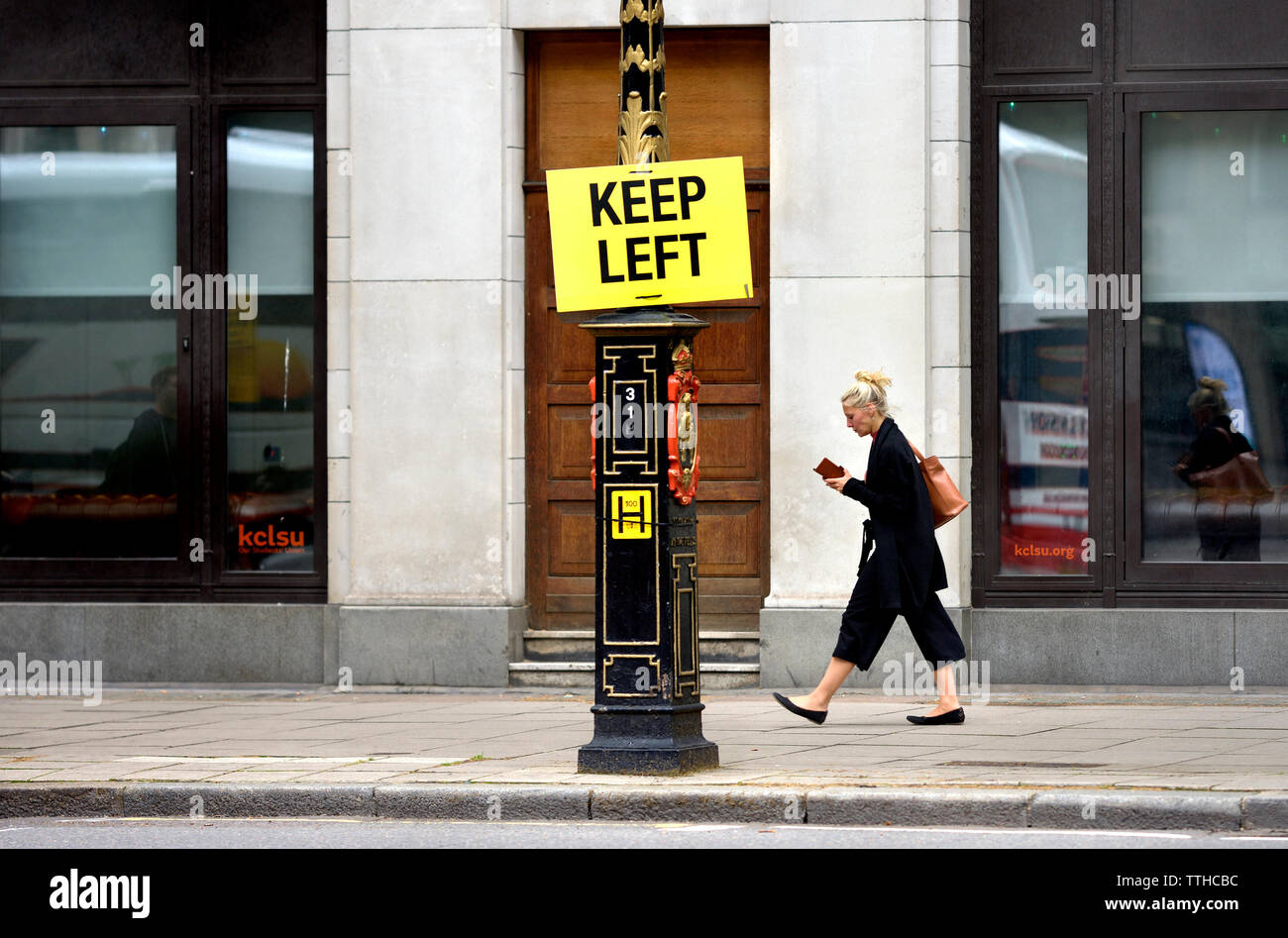 London, England, UK. Keep Left sign in Fleet Street. Woman on her mobile phone walking past Stock Photo