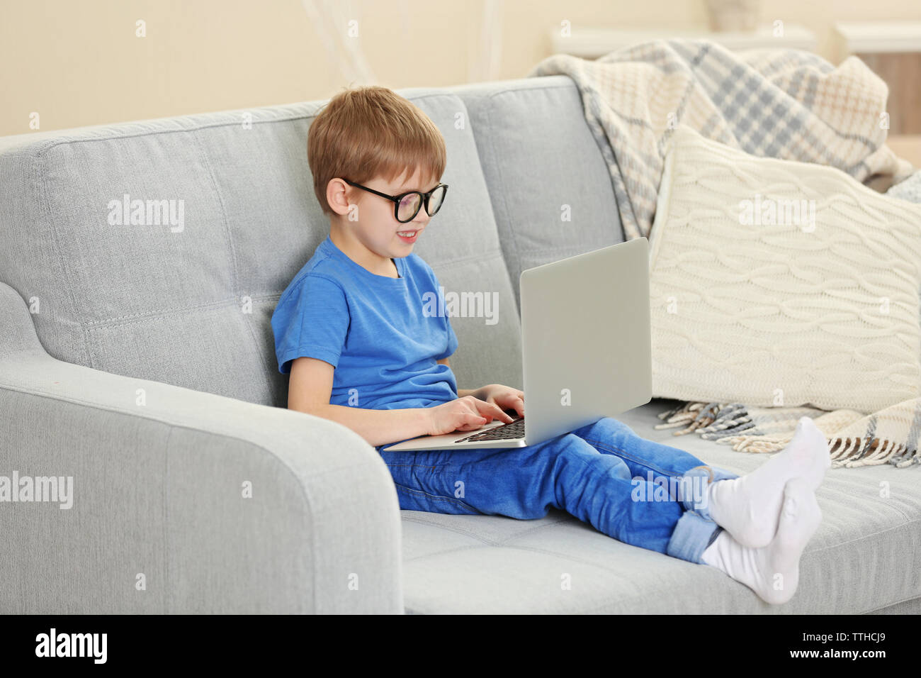 Little boy using laptop on sofa indoors Stock Photo - Alamy