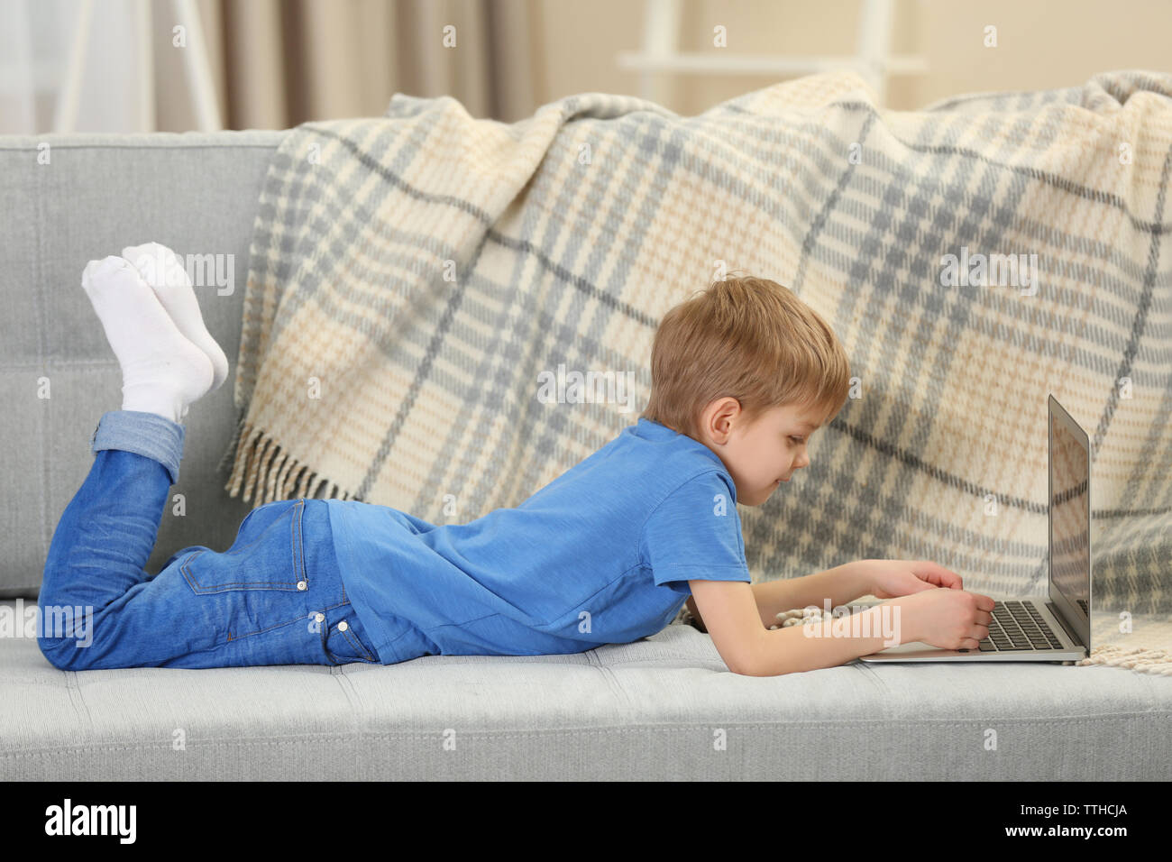 Little boy using laptop on sofa indoors Stock Photo - Alamy