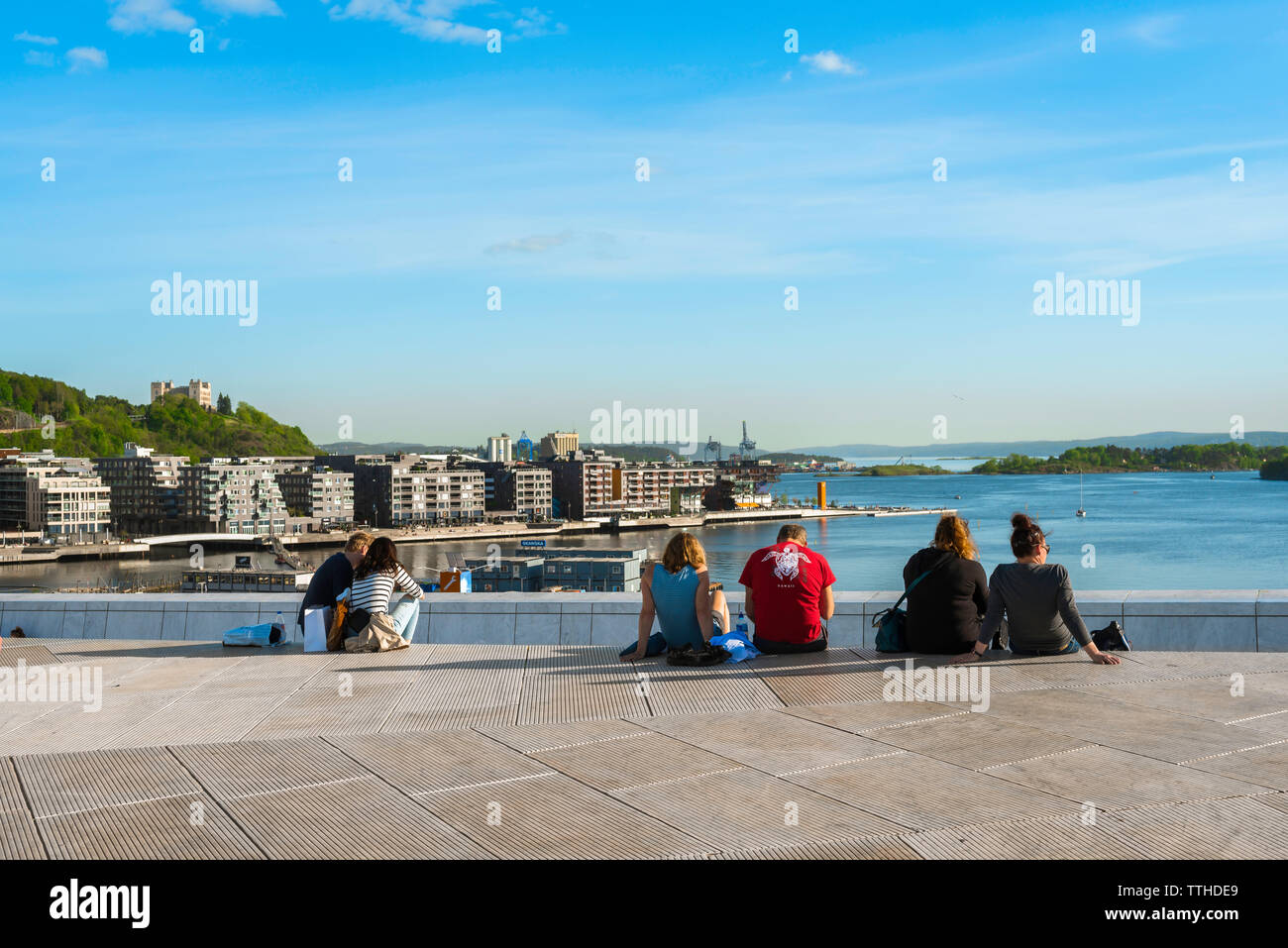 Oslofjord, rear view in summer of people sitting on the roof of the Oslo Opera House Building looking towards the Oslofjord harbor, Norway. Stock Photo
