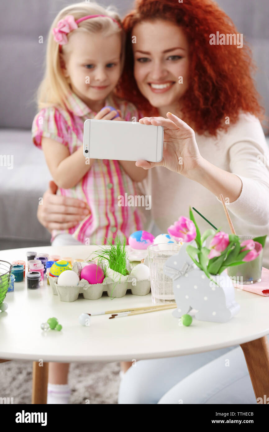 Mother and daughter making selfie while decorating Easter eggs, indoors Stock Photo