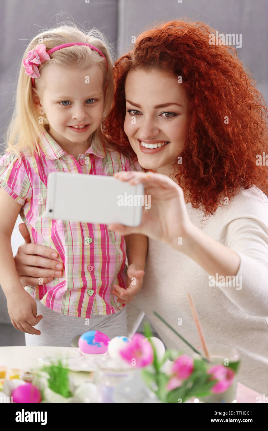 Mother and daughter making selfie while decorating Easter eggs, indoors Stock Photo