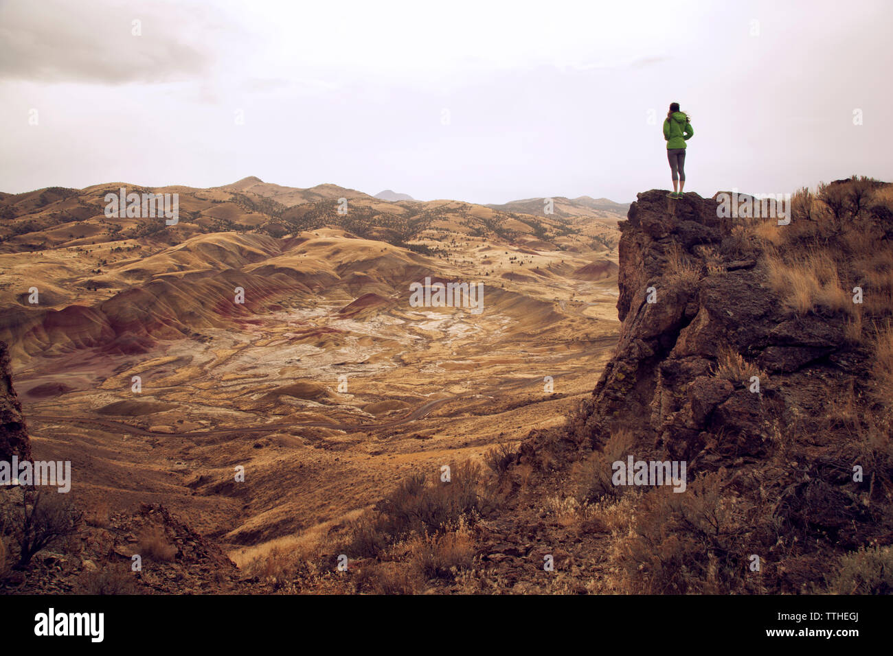 Woman standing on cliff against mountains Stock Photo