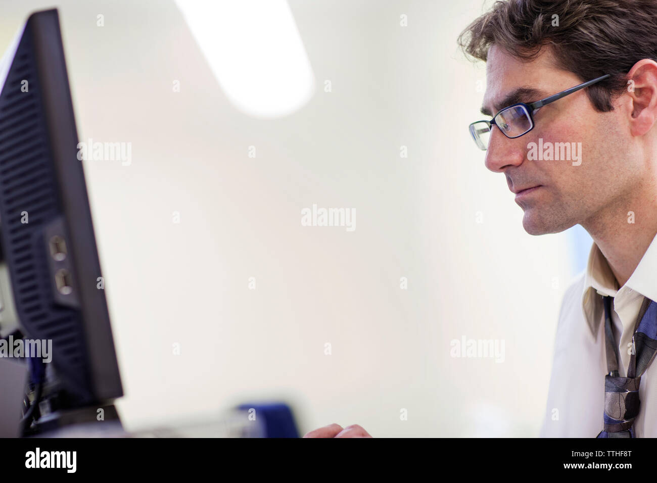 Side view of serious dentist using computer at clinic Stock Photo