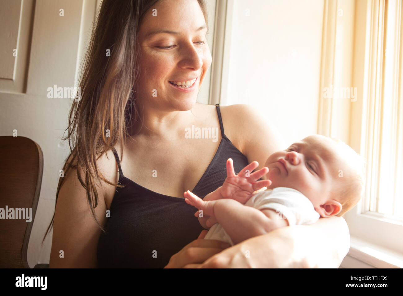 Happy mother carrying baby girl at home Stock Photo