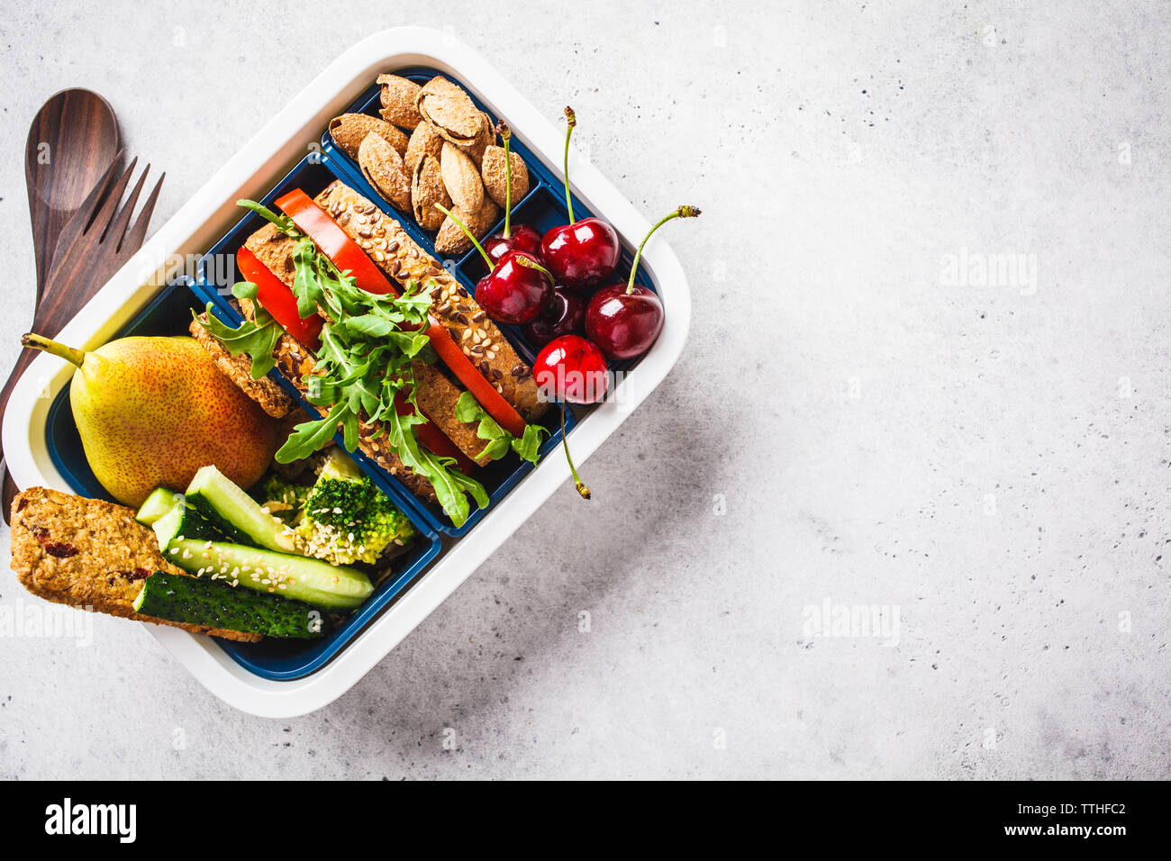 https://c8.alamy.com/comp/TTHFC2/lunch-box-with-sandwich-pear-vegetables-nuts-and-snacks-on-a-gray-background-top-view-copy-space-TTHFC2.jpg