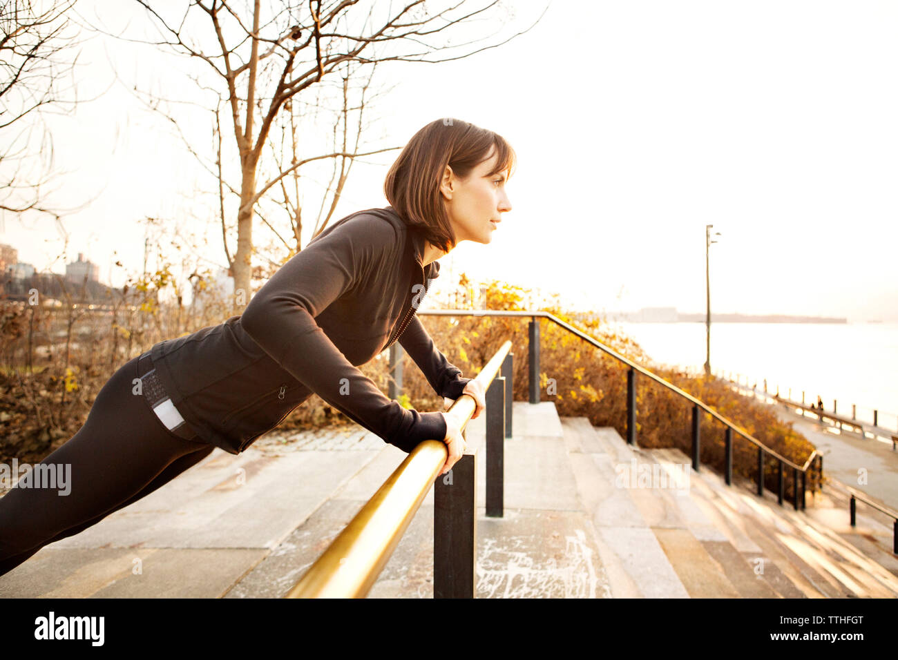 Woman doing push-ups on railing Stock Photo