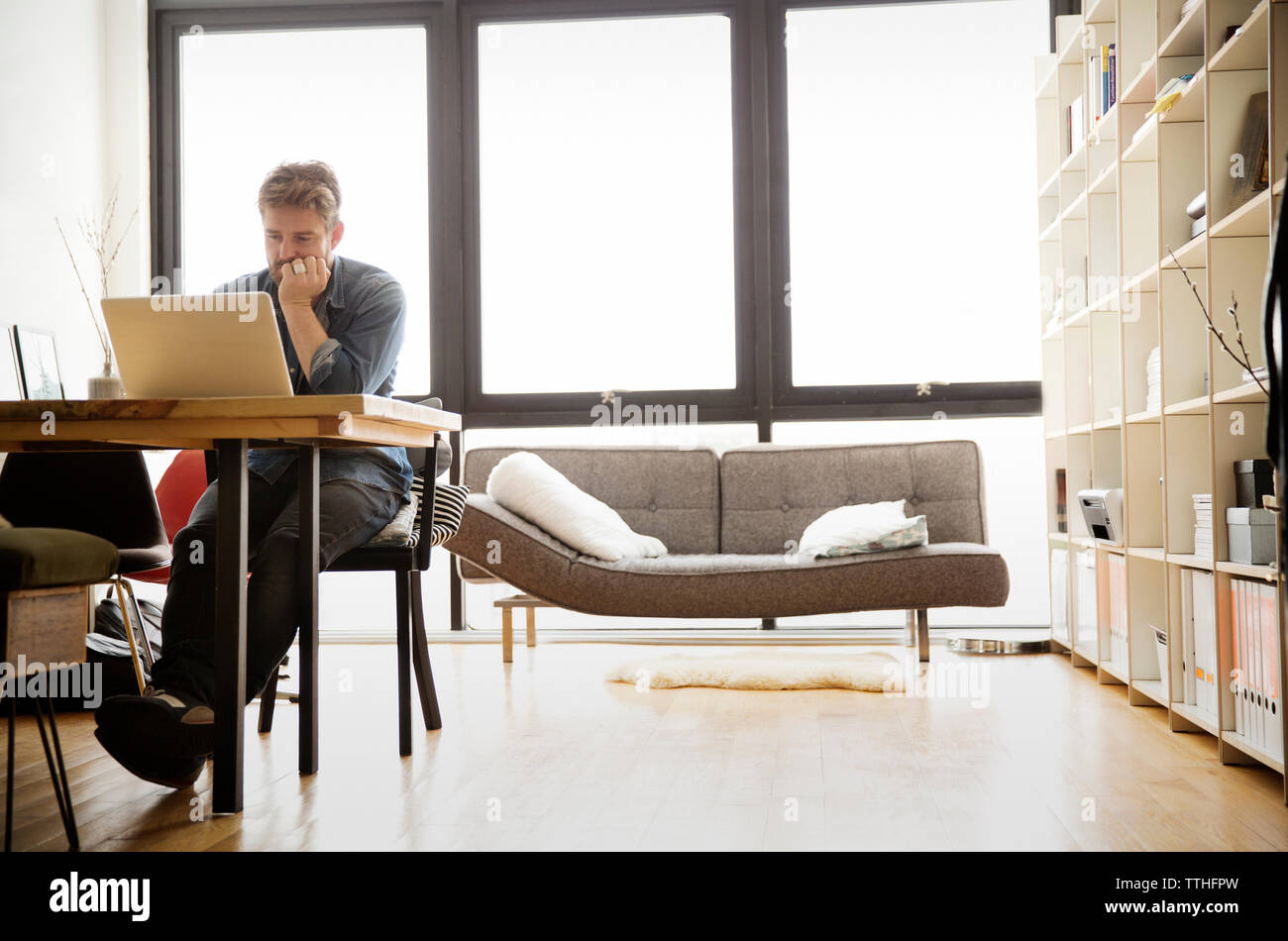 Concentrated man using laptop while sitting at table Stock Photo