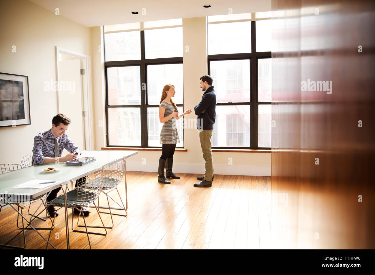 businessman using phone while colleagues having discussion in background Stock Photo
