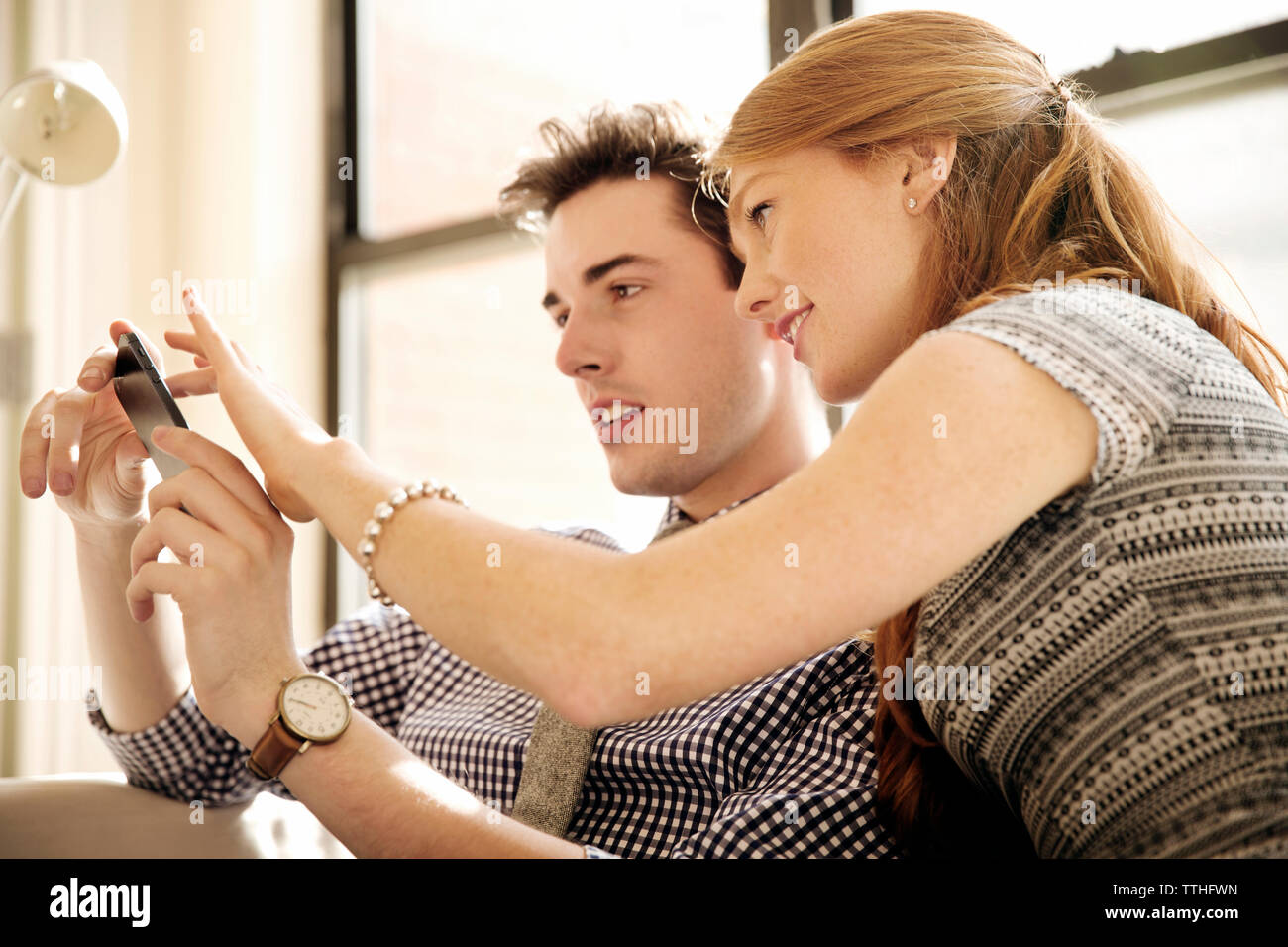 Colleagues using phone while sitting in office Stock Photo