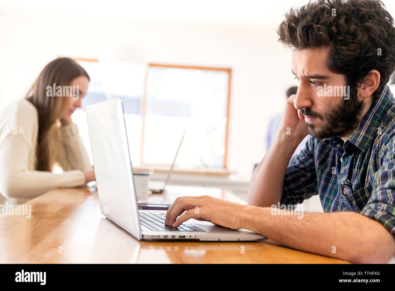 Man and woman using laptop while sitting at table Stock Photo