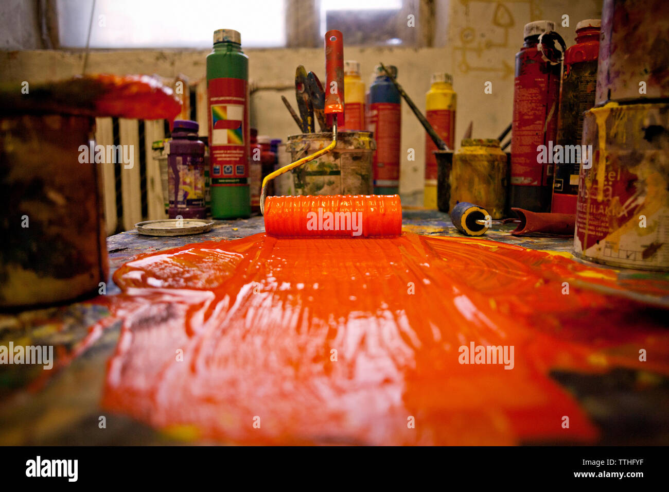Surface level of orange paint and roller on table Stock Photo
