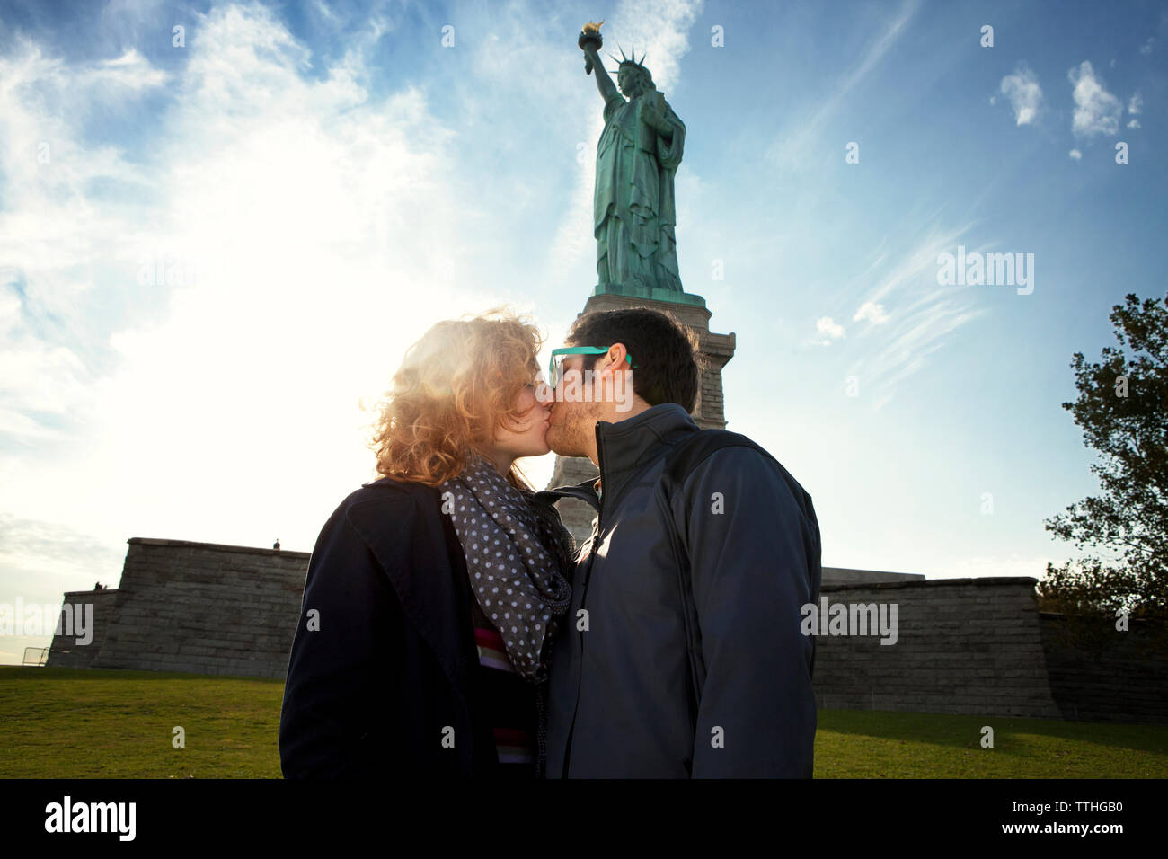Couple kissing while standing against Statue of Liberty Stock Photo