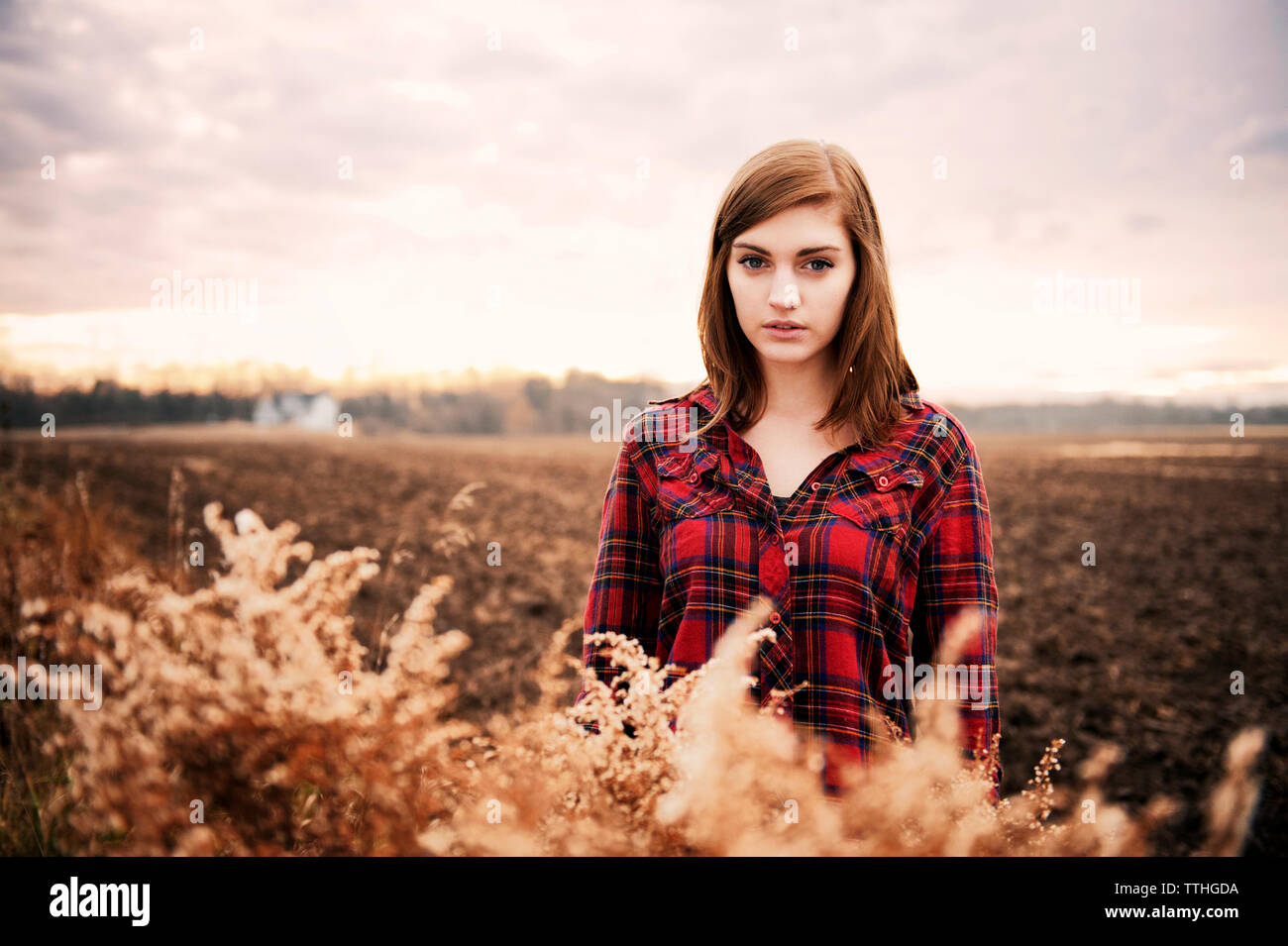 Portrait of beautiful woman standing on field against sky Stock Photo ...
