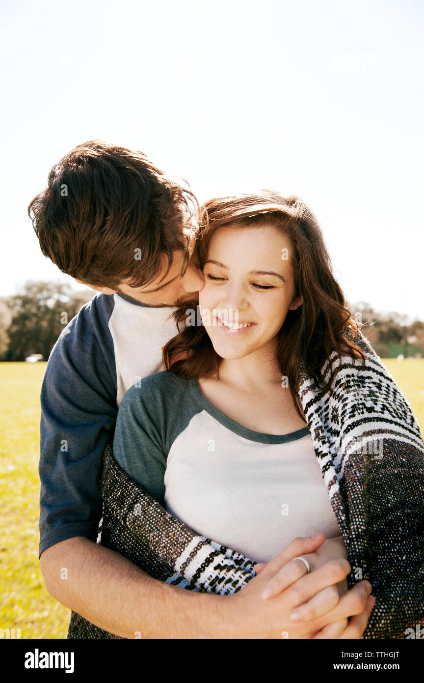 Man embracing girlfriend while kissing at park Stock Photo