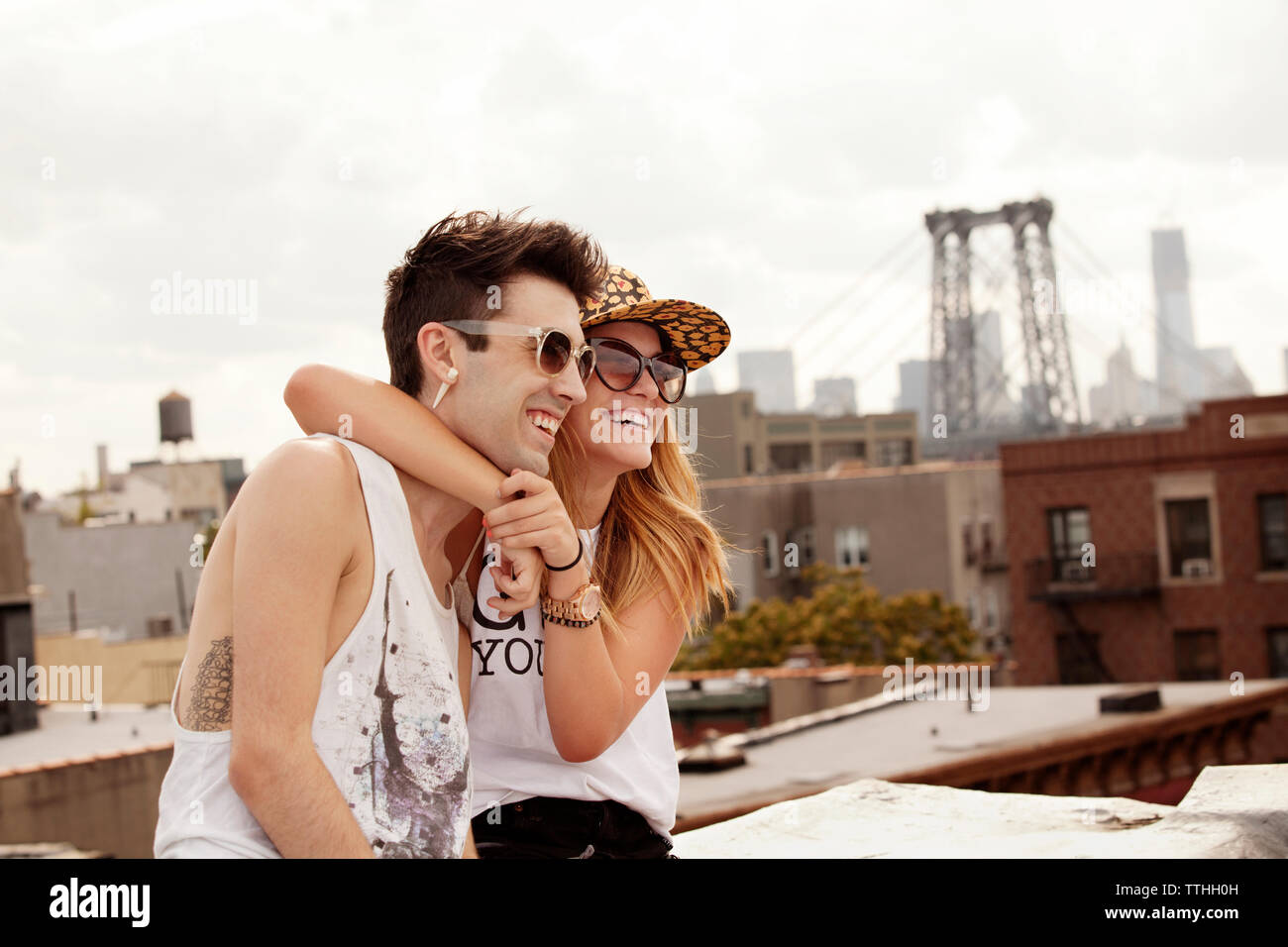 Cheerful woman embracing boyfriend at building terrace Stock Photo